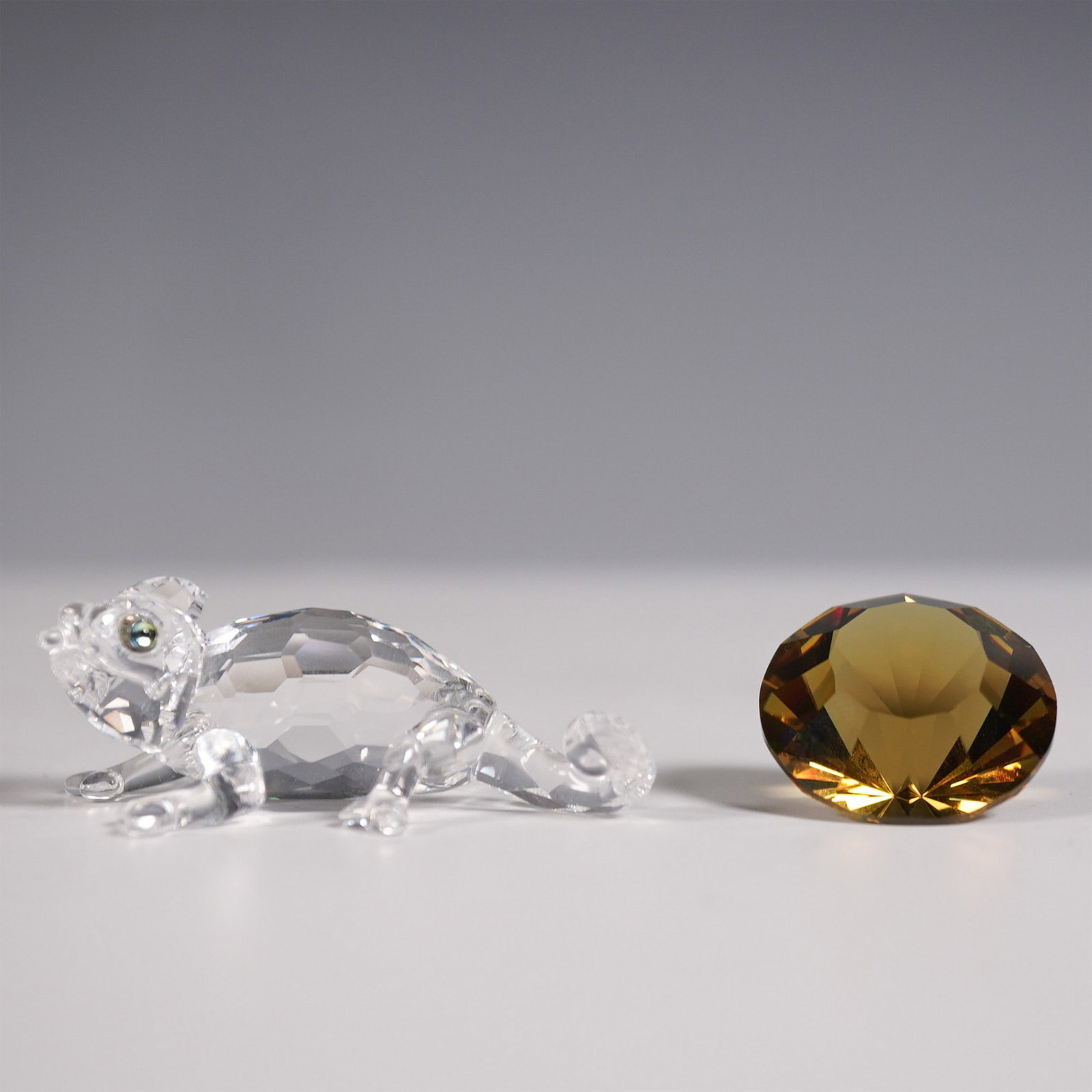 2pc Swarovski Crystal Figurine, Chameleon and Faceted Gem: This Swarovski crystal set includes a charming faceted crystal chameleon with intricate detailing and iridescent green eyes, paired with a separate faceted gem that shifts between warm amber and mossy