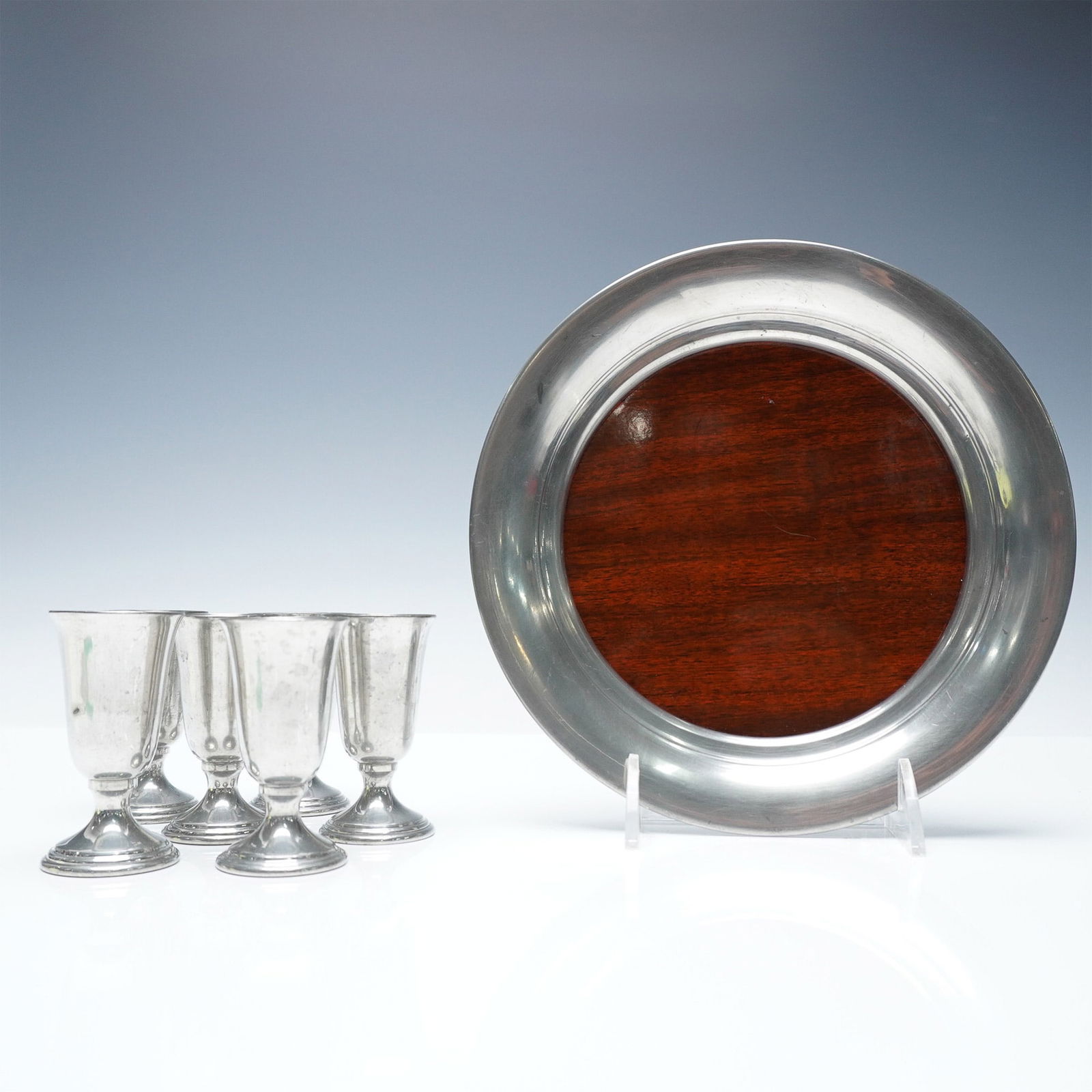7pc Revere Pewter Cordials and Tray Set: A refined set of six Revere Pewter cordials accompanied by a matching tray with a wooden insert. The cordials feature a classic fluted design with a pedestal base, ideal for serving liqueurs. The tray