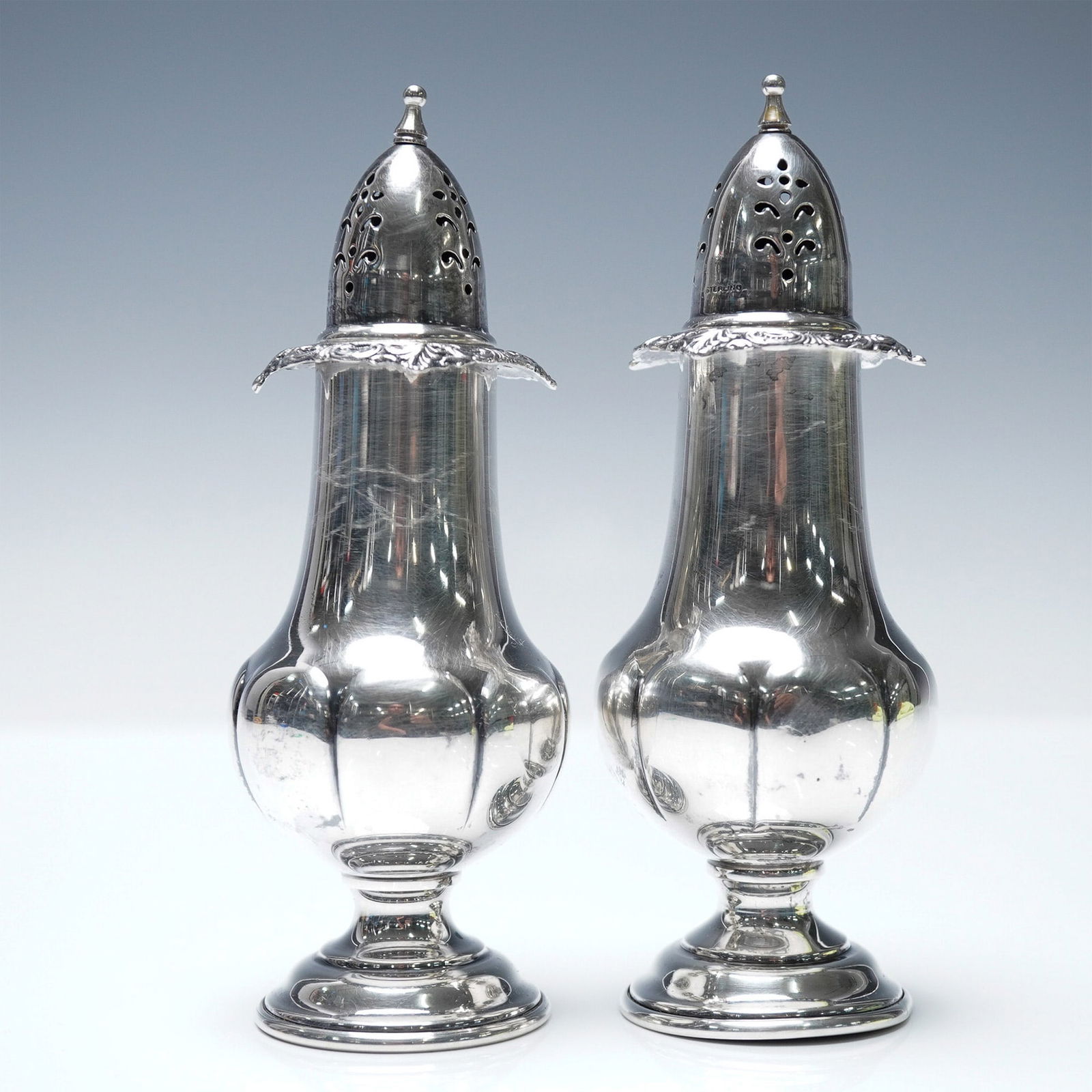 2pc Wallace Sterling Salt and Pepper Shakers, Baroque Grande: A pair of sterling silver salt and pepper shakers by Wallace Silversmiths in the Baroque Grande pattern. Featuring an elegant curved body with pierced removable tops and intricate floral motifs around