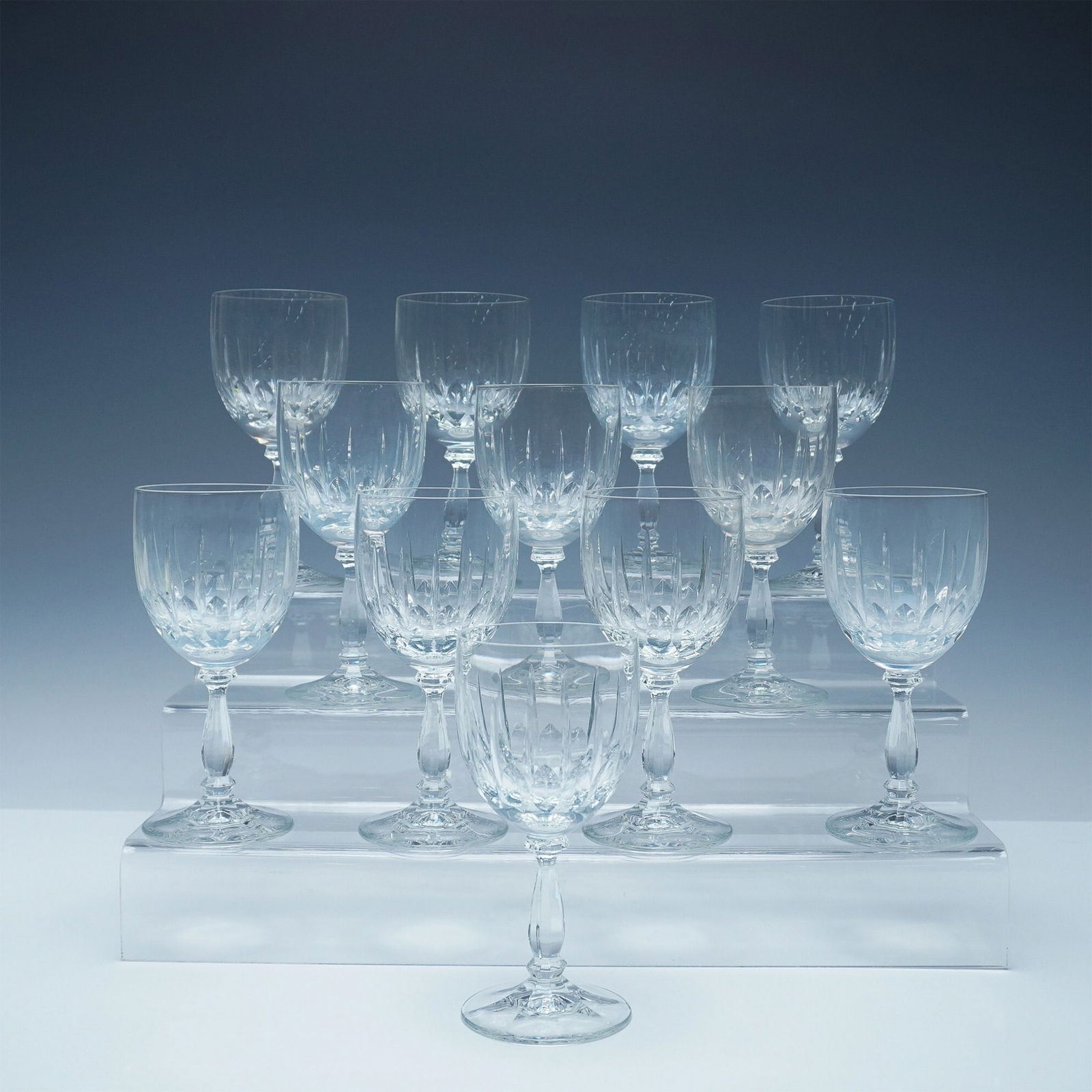 Set of 12 Cut Crystal Goblets: A set of twelve finely crafted cut crystal goblets featuring a classic deep-cut diamond and wedge pattern. Each goblet showcases brilliant clarity and expert craftsmanship, with a faceted stem and a g