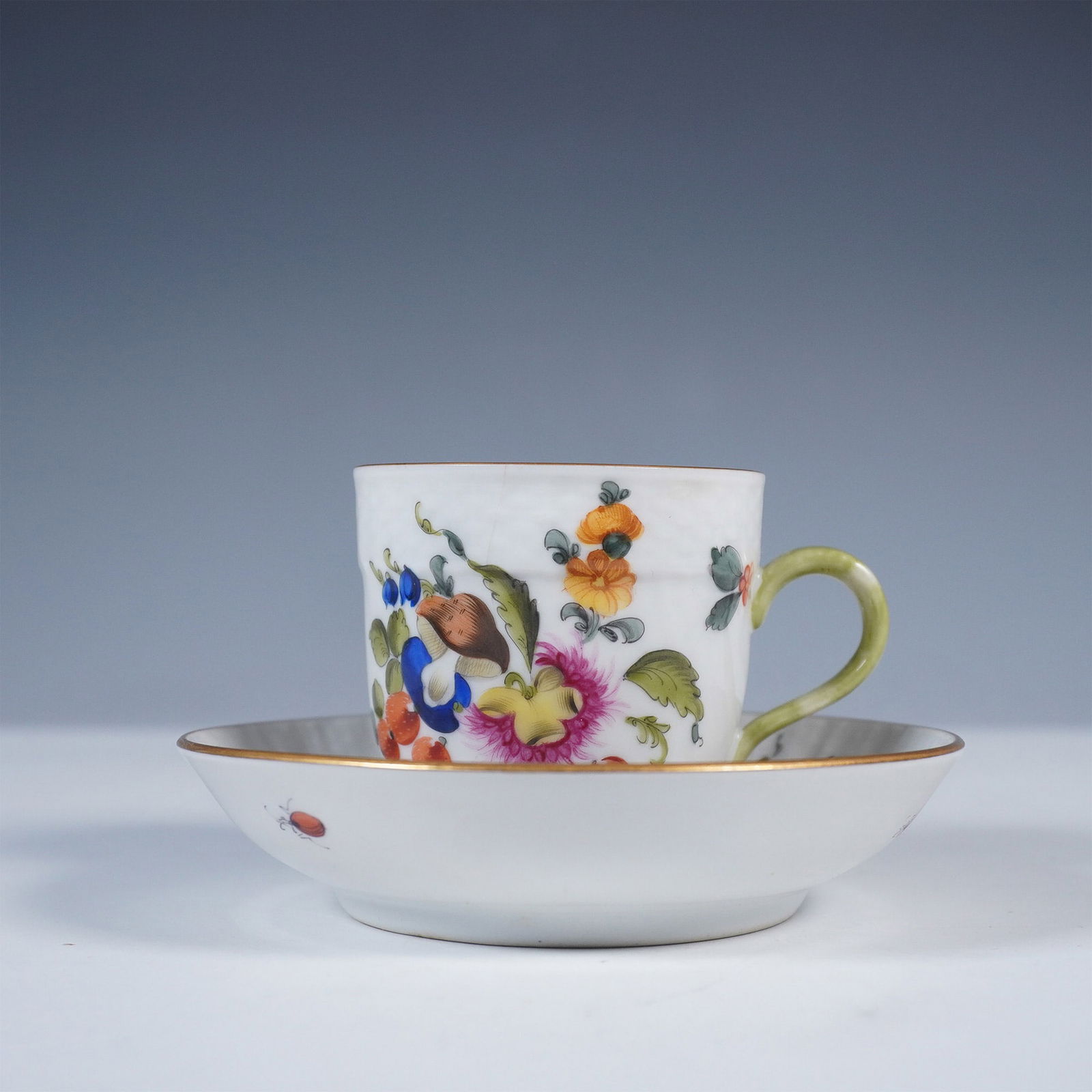Herend Porcelain Cup and Saucer, Fruits and Flowers 1709 BFR: Charming hand-painted porcelain demitasse cup and saucer set by Herend of Hungary, featuring the vibrant Fruits and Flowers pattern. The cup showcases an intricate still-life composition of fruits, fl