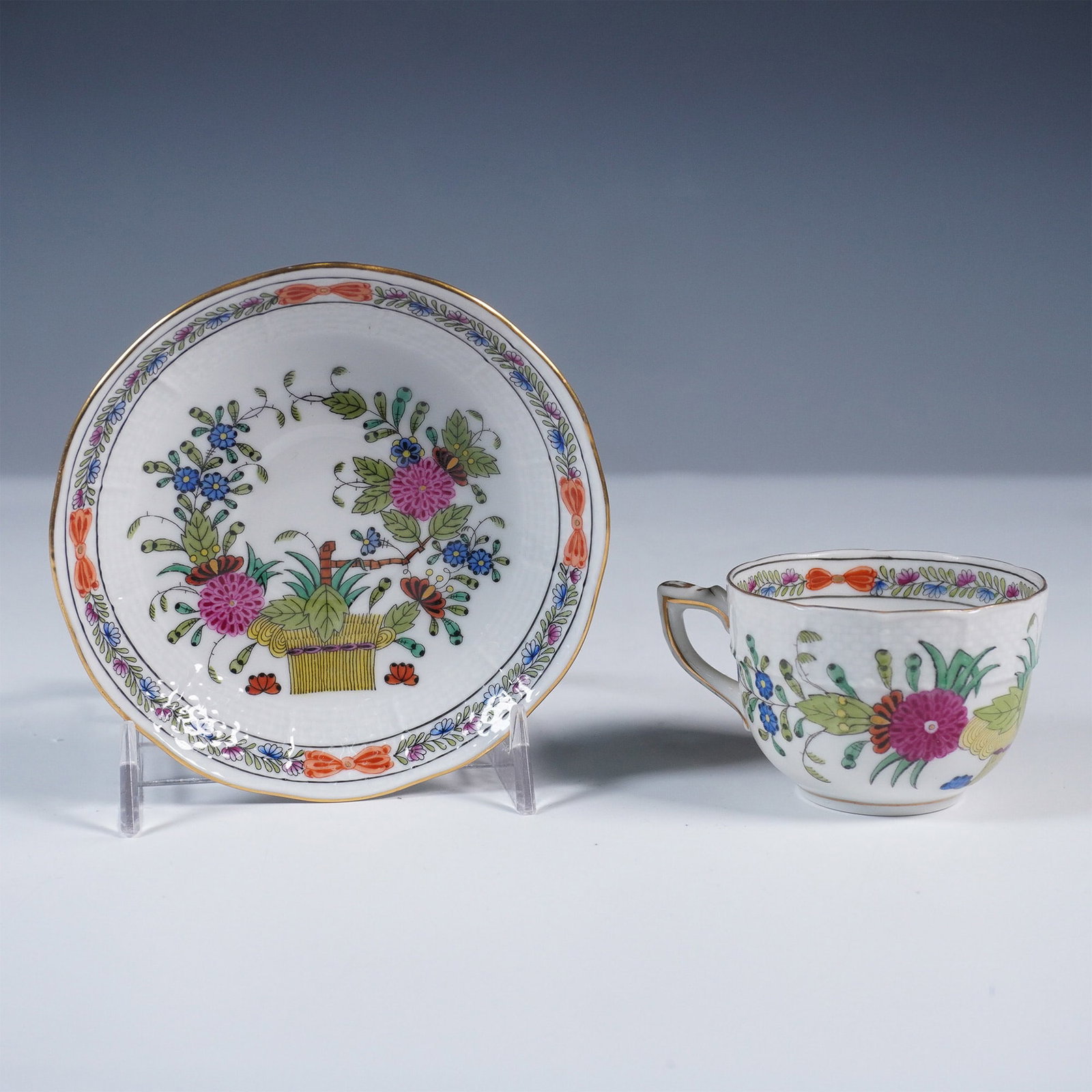 Herend Porcelain Demitasse Cup and Saucer, Indian Basket Multicolor: Herend porcelain demitasse cup and saucer set in the vibrant Indian Basket Multicolor pattern. This hand-painted design features an intricate floral motif with a central woven basket in rich hues of p