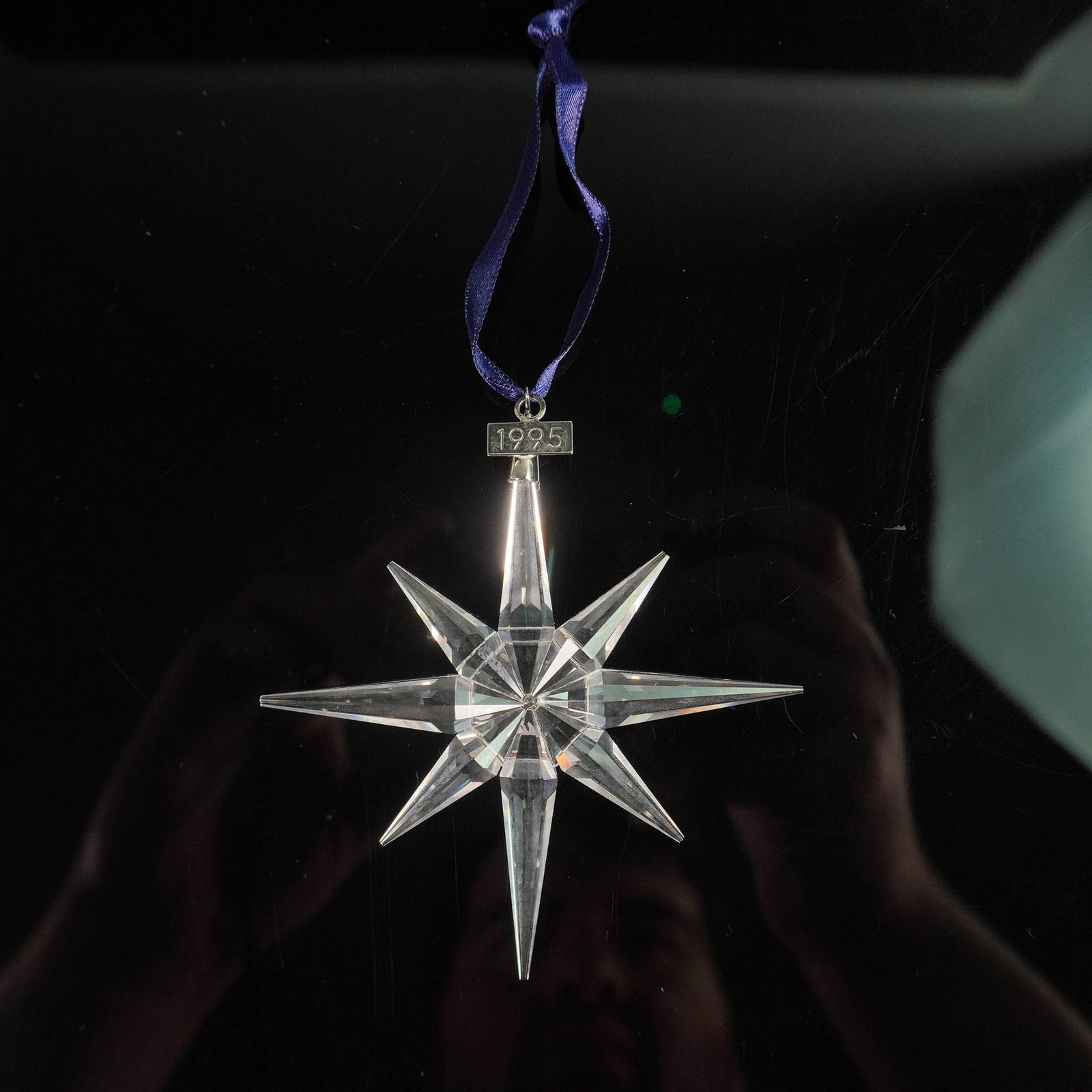 Swarovski 1995 Annual Edition Star Ornament with Box: Swarovski crystal holiday ornament from the 1995 Annual Edition collection, designed as an eight-pointed faceted star suspended from a blue ribbon with a metal tag engraved 1995. Known for its elegant