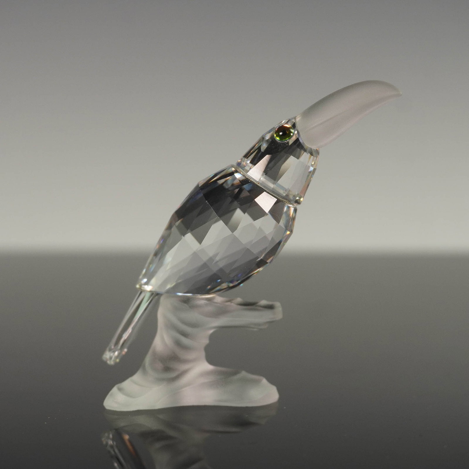 Swarovski Crystal Figurine, Toucan on Branch: Swarovski crystal figurine titled Toucan, from the Up in the Trees series. This striking piece features a clear faceted crystal toucan with a frosted beak and perched on a frosted crystal branch. The 
