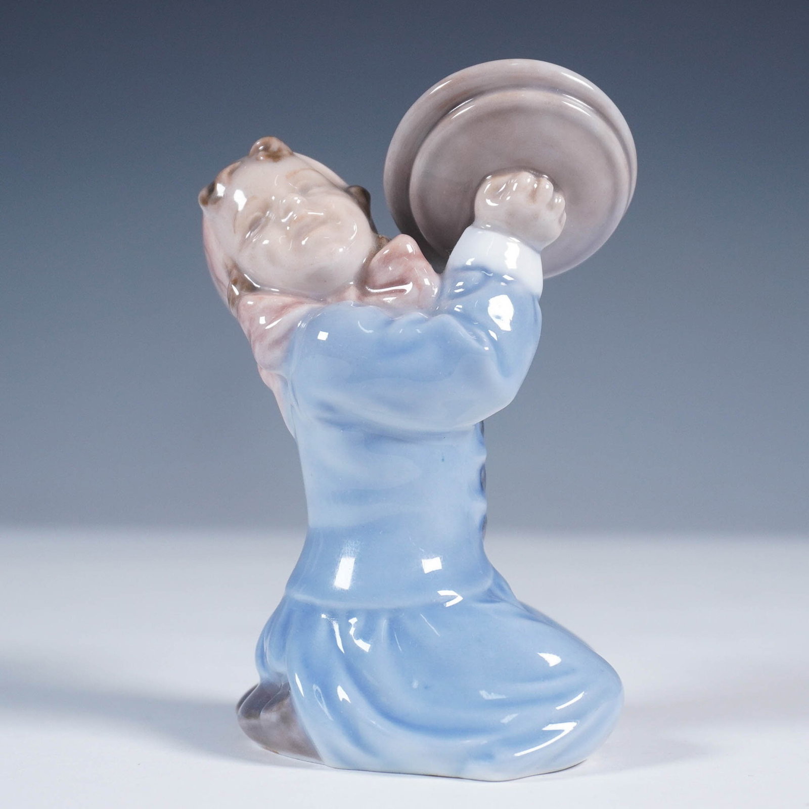 Royal Copenhagen Porcelain Figurine, Girl with Cymbals No. 3677: Crafted by the renowned Royal Copenhagen of Denmark, this porcelain figurine features a young girl joyfully clashing cymbals. Model number 3677, the piece is rendered in soft pastel tones with a gloss