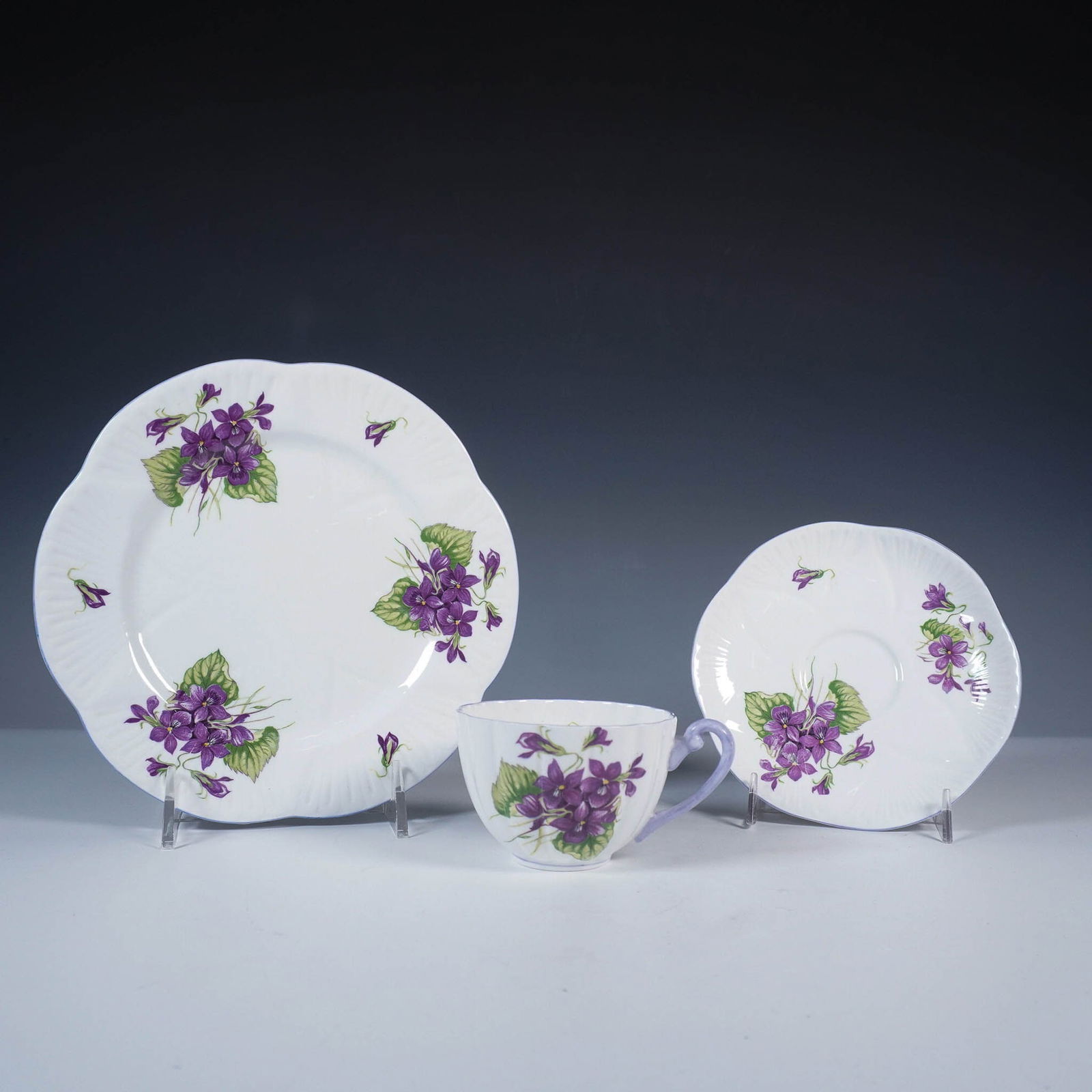 3pc Shelley Fine Bone China Violets Tea Trio Set: Shelley fine bone china tea trio featuring the delicate Violets pattern, number 13821. This set includes a scalloped-edge luncheon plate, a matching saucer, and a teacup with an ornate lavender handle