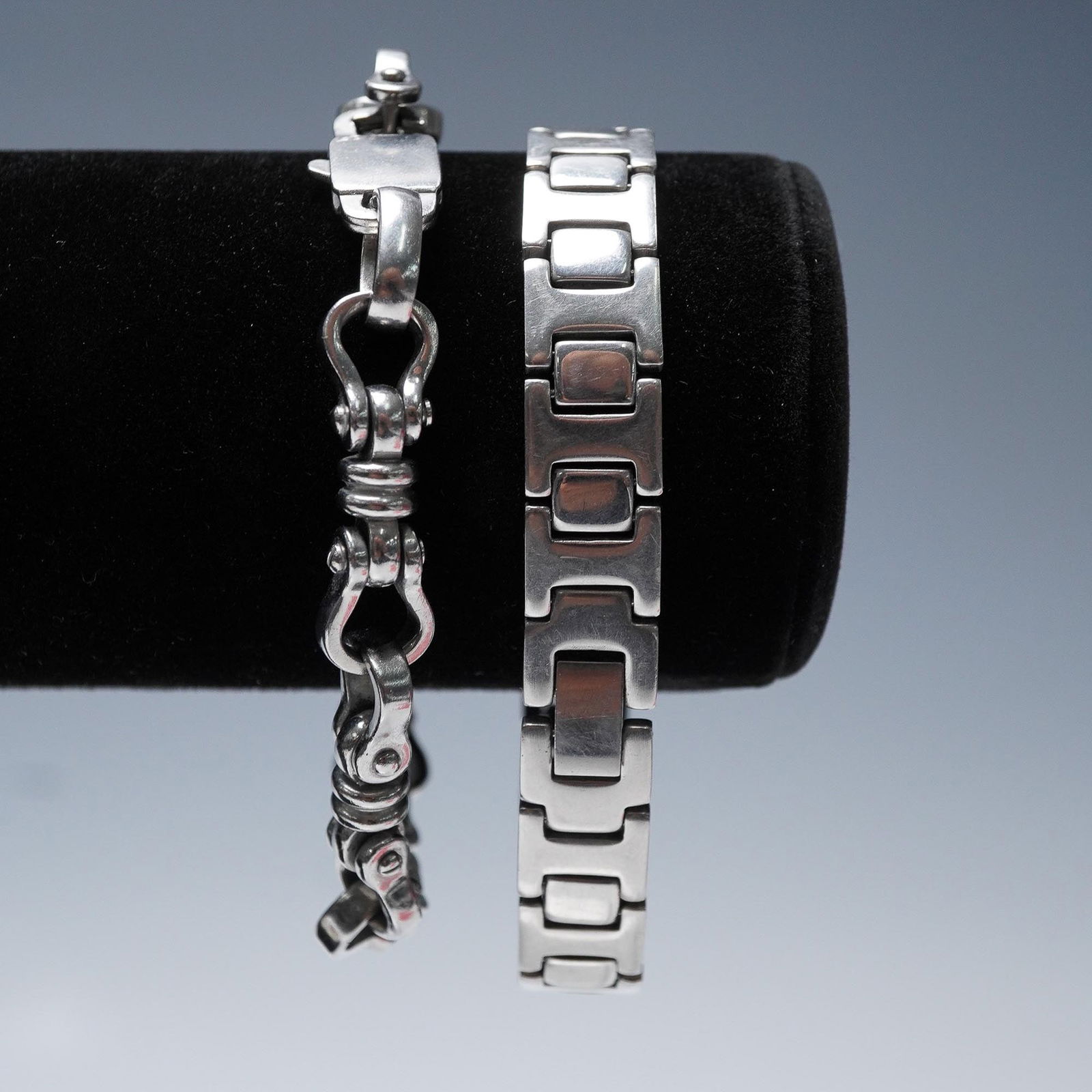 2pc Stainless Steel Link Bracelets: Pair of stainless steel link bracelets featuring bold industrial designs. One bracelet showcases a chunky curb-link style with mechanical accents and a secure fold-over clasp, while the other features