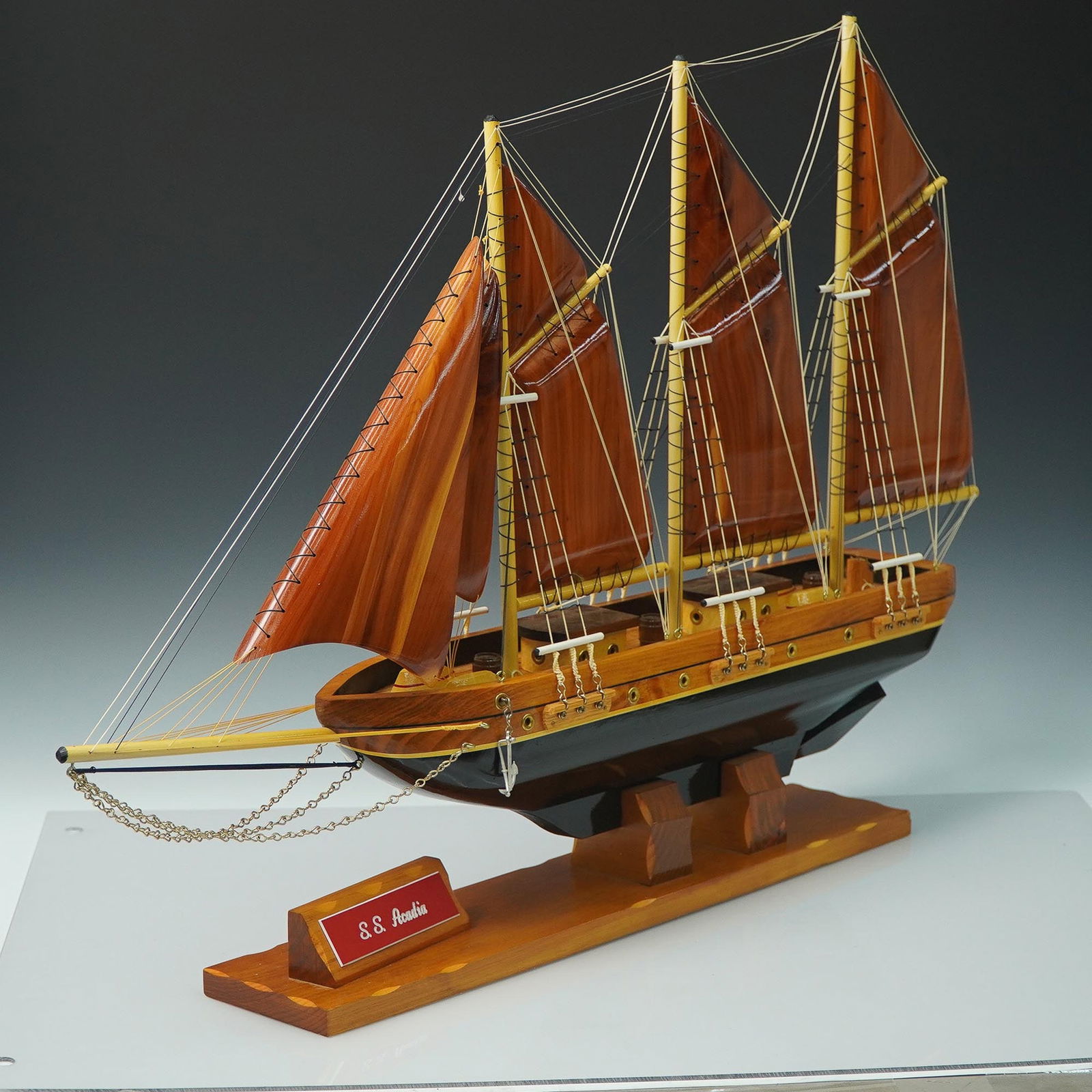 Wooden Model Ship, S.S. Acadia, 3-Masted Schooner: Detailed wooden model ship of the S.S. Acadia, a three-masted schooner-style vessel crafted with rich wood tones and rigging accents. Displayed on a wood base with a nameplate, this handcrafted model