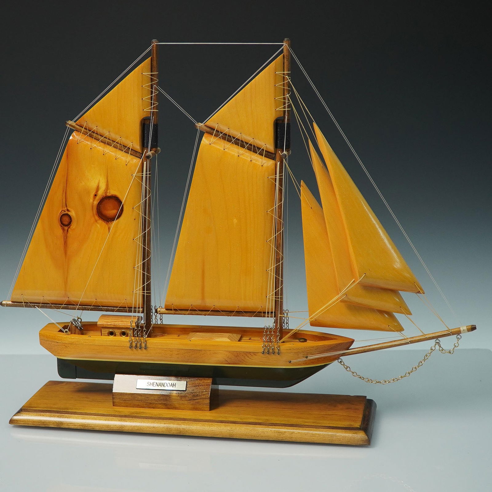 Wooden Model Ship, Shenandoah, 2-Masted Schooner: Handcrafted wooden model ship representing the Shenandoah, a classic two-masted schooner. Constructed with warm-toned wood sails, intricate rigging, and deck details, this model is mounted on a staine