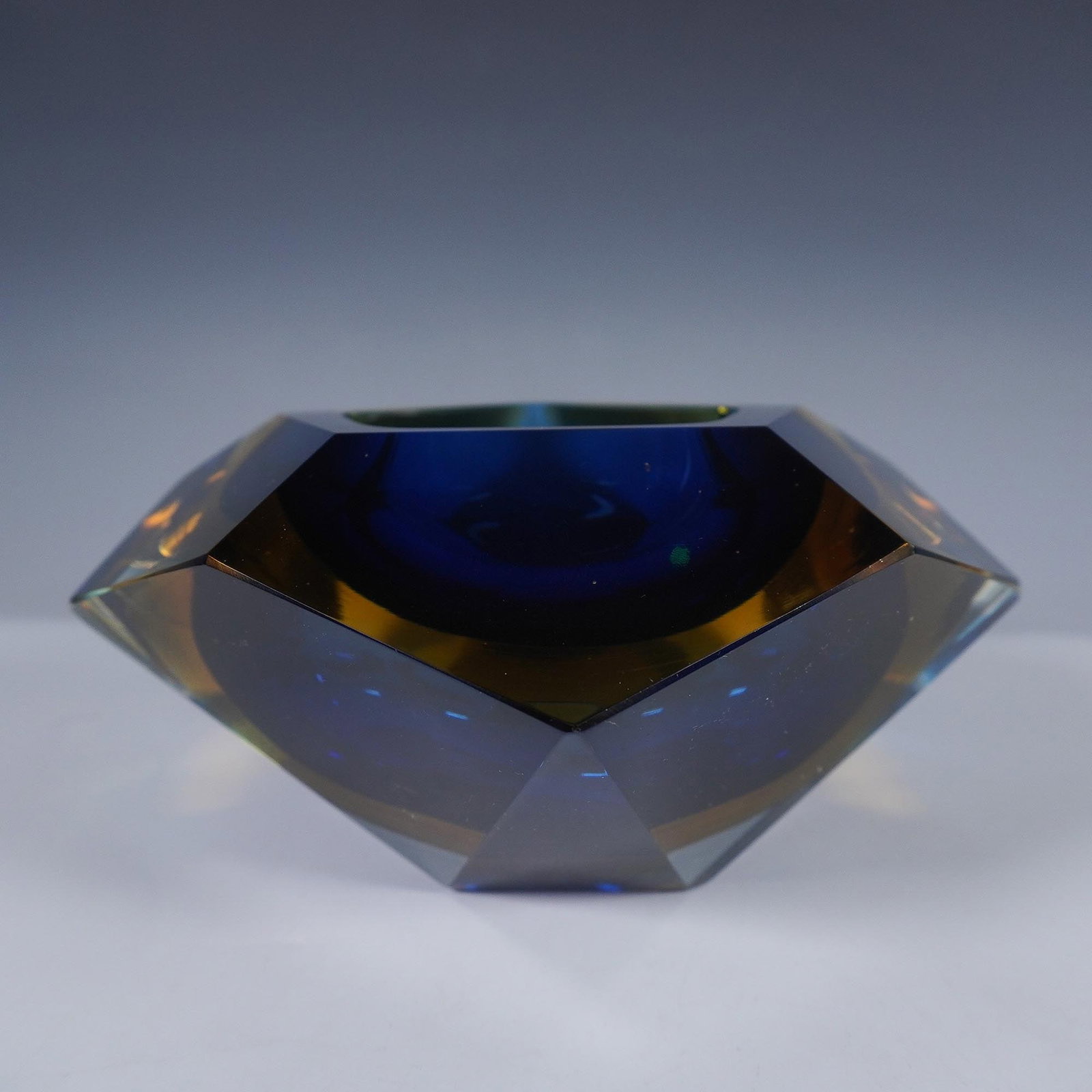Sommerso Glass Faceted Bowl: Beautifully designed clear, amber and blue glass bowl. With striking jeweled styled cuts that illuminates the blend of these colors with the cobalt center accenting the exterior colors. This bowl woul