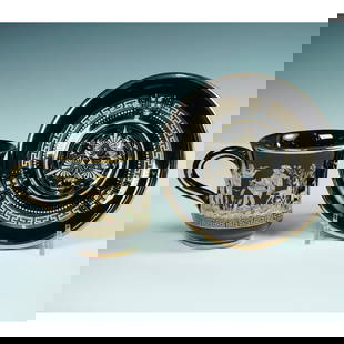 2pc Greek Black Porcelain Cup and Saucer with 24K Gold Mythological Design: Elegant black porcelain teacup and matching saucer richly decorated with intricate mythological scenes in 24K gold. The cup features a continuous frieze of classical figures in a pastoral setting, inc
