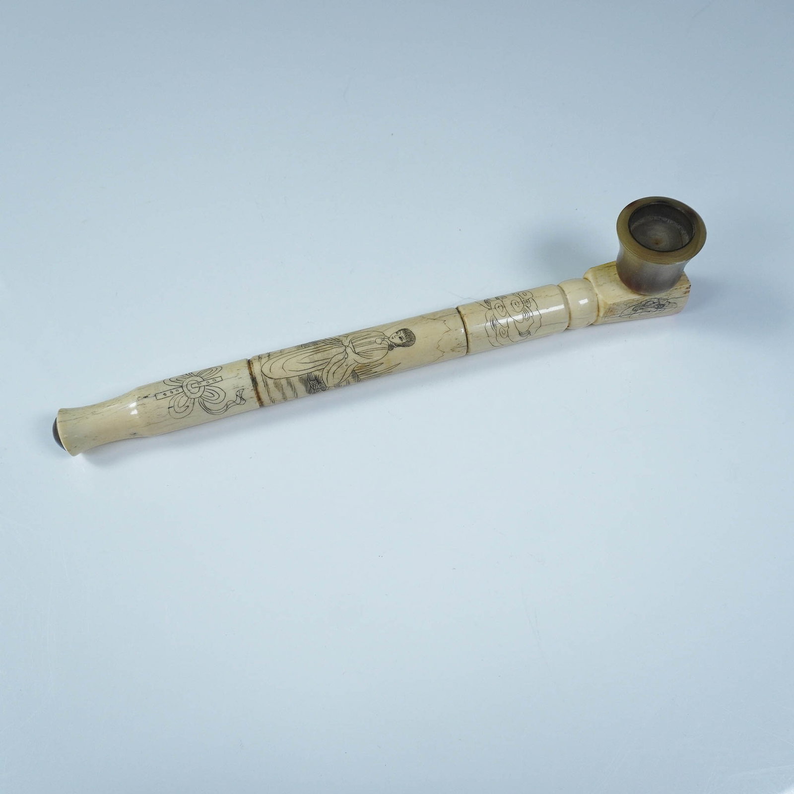 Carved Pipe with Scrimshaw Style Detailing and Horn Bowl: Intricately crafted long-stem pipe featuring detailed decorative carvings along the bone or bone-like shaft, including a robed female figure and ornate linework. The bowl is made from polished natural