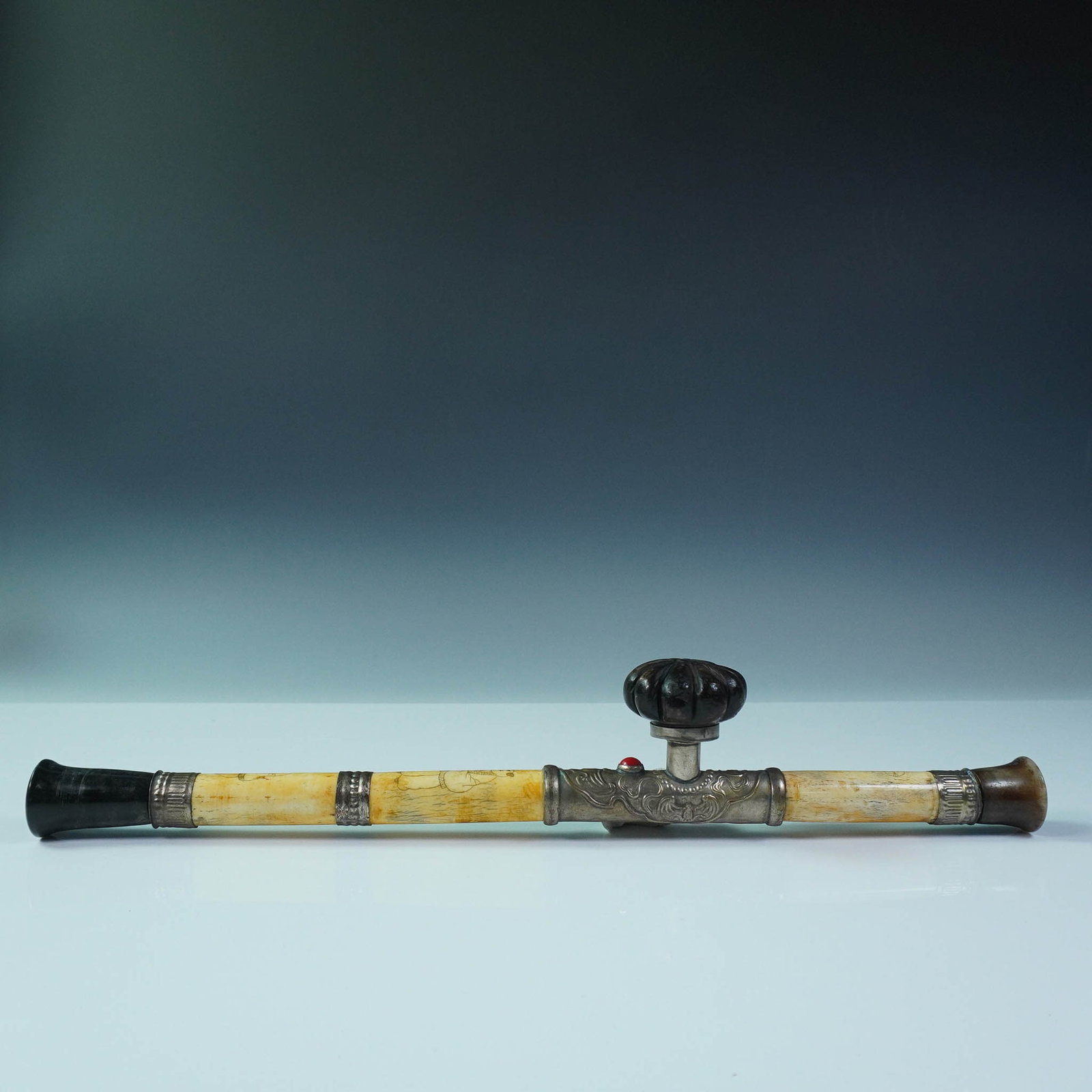 Chinese Opium Pipe with Carved Bone and Metal Fittings: Chinese opium pipe featuring scrimshawed bone segments decorated with incised depictions of traditional figures. The central section is crafted with embossed metal detailing and a carved knob adorned 