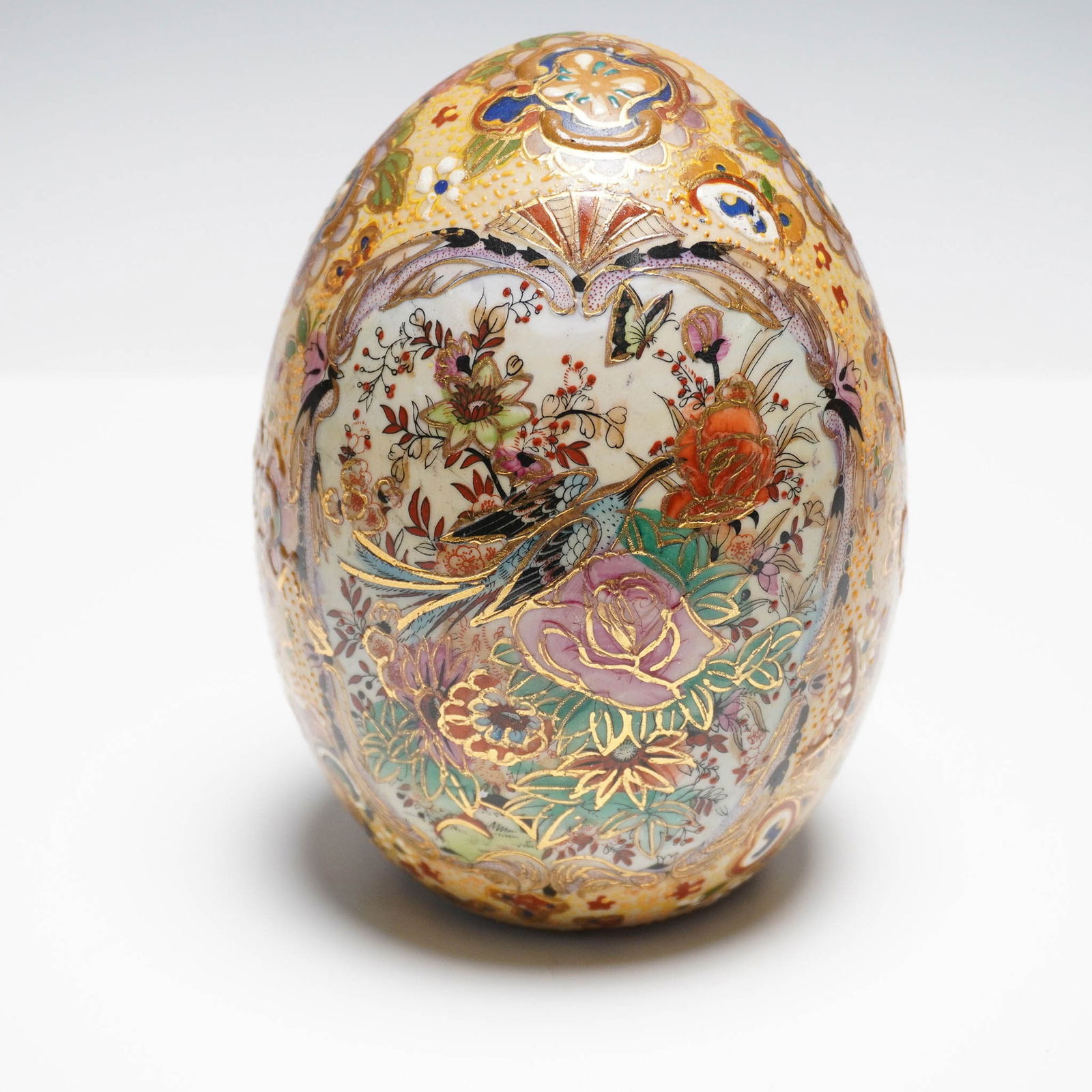Satsuma Style Decorative Egg, Floral and Bird Motif: Satsuma-style decorative egg featuring elaborate hand-painted designs with birds, butterflies, and vibrant floral motifs. This ornamental egg is richly embellished with gilt detailing and traditional