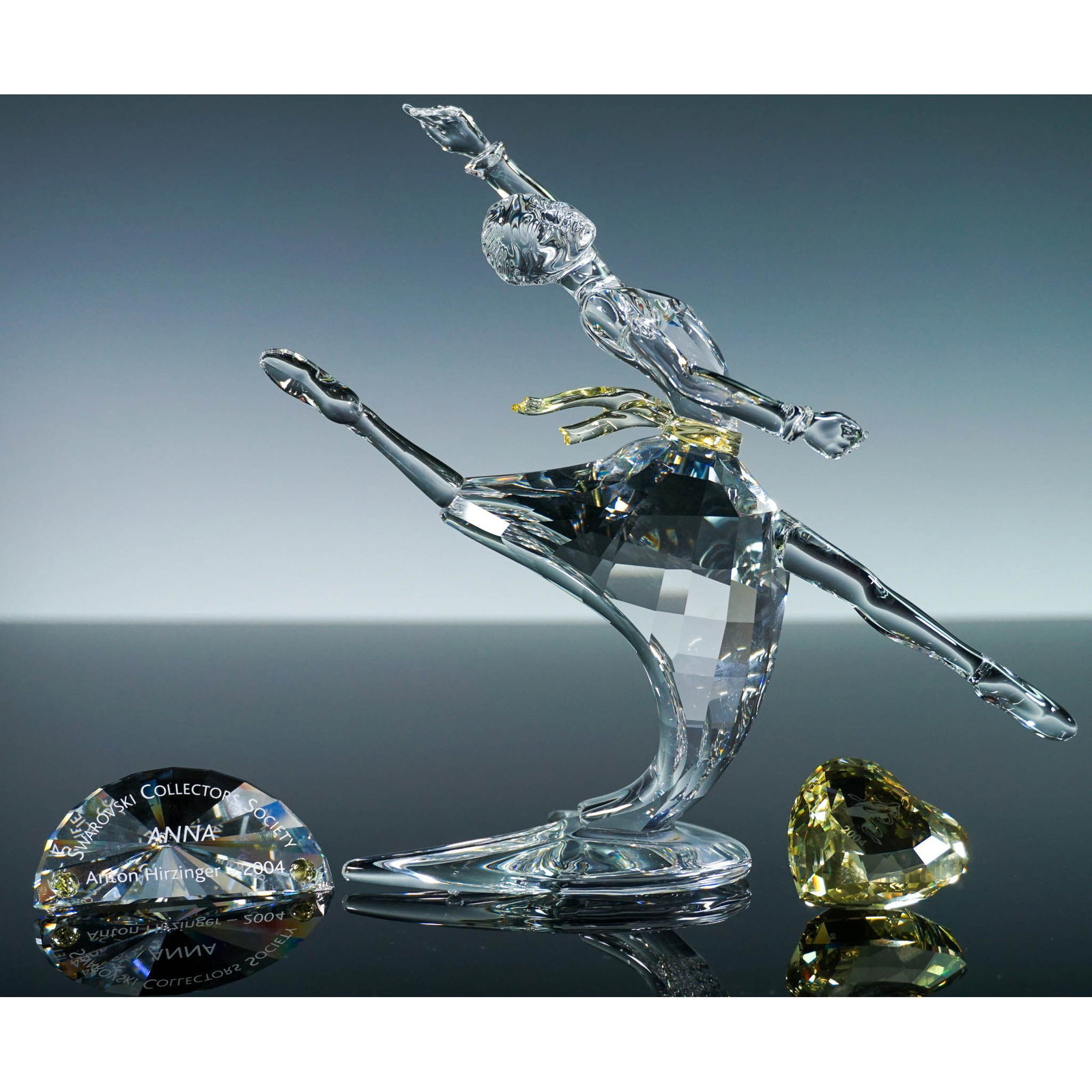 3pc Swarovski Crystal Figurine, Magic of Dance Anna with Plaque and Heart: Gracefully sculpted from faceted clear crystal, this Swarovski figurine titled Anna represents the 2004 Annual Edition of the Magic of Dance trilogy. Designed by Anton Hirzinger for the Swarovski Crys