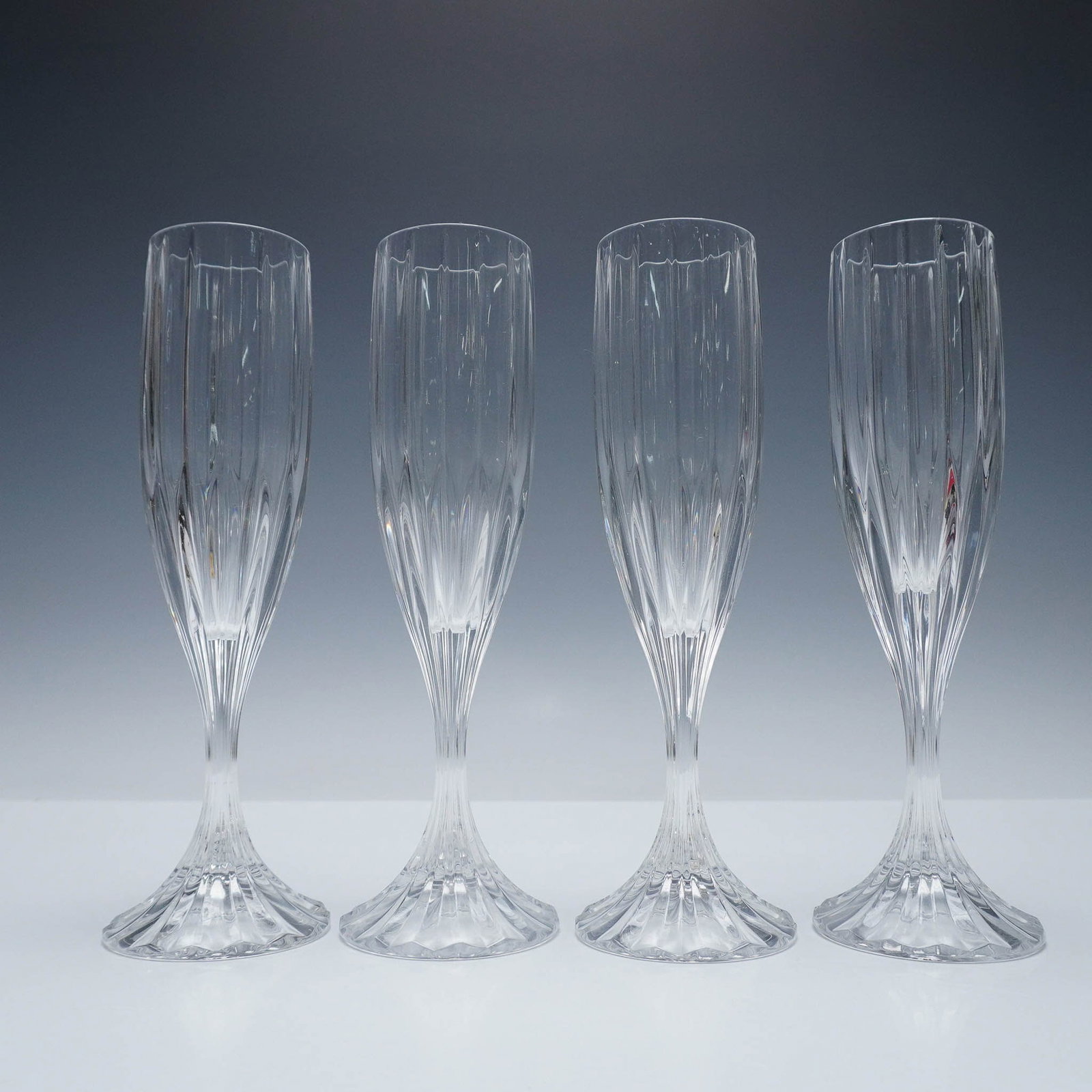 4pc Fluted Champagne Glasses, Park Lane by Mikasa: Set of four crystal fluted champagne glasses from the Park Lane collection by Mikasa. Featuring a vertically paneled design with graceful stems and starburst bases, these elegant flutes are ideal for 