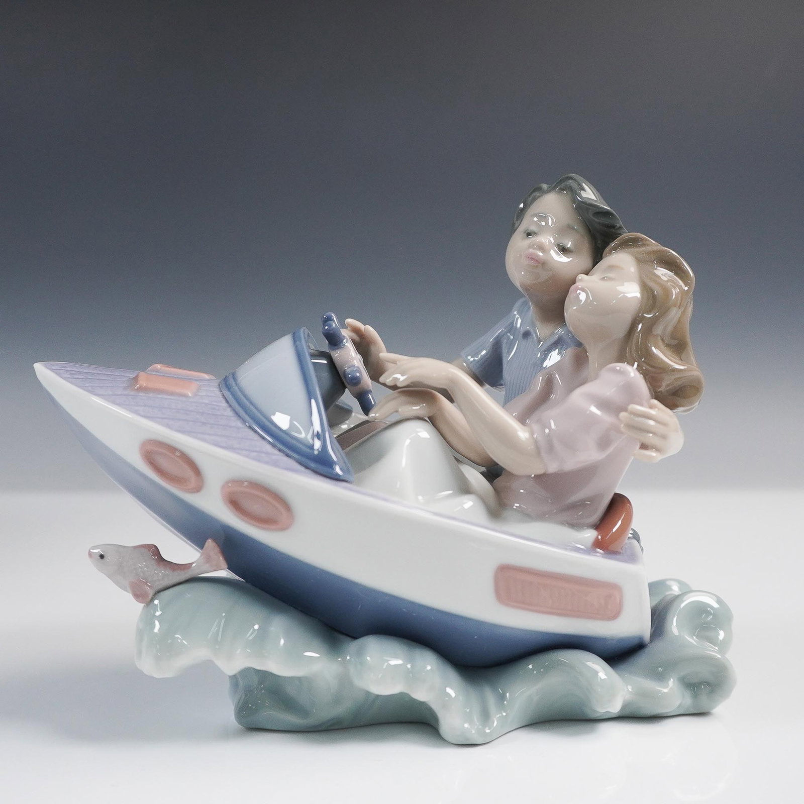 Lladro Porcelain Figurine Riding the Waves 01005941: Lladro figurine titled Riding the Waves, model 01005941, sculpted by Joan Coderch. Issued in 1992 and retired in 1997, this playful and romantic piece features a couple riding a speedboat over curling