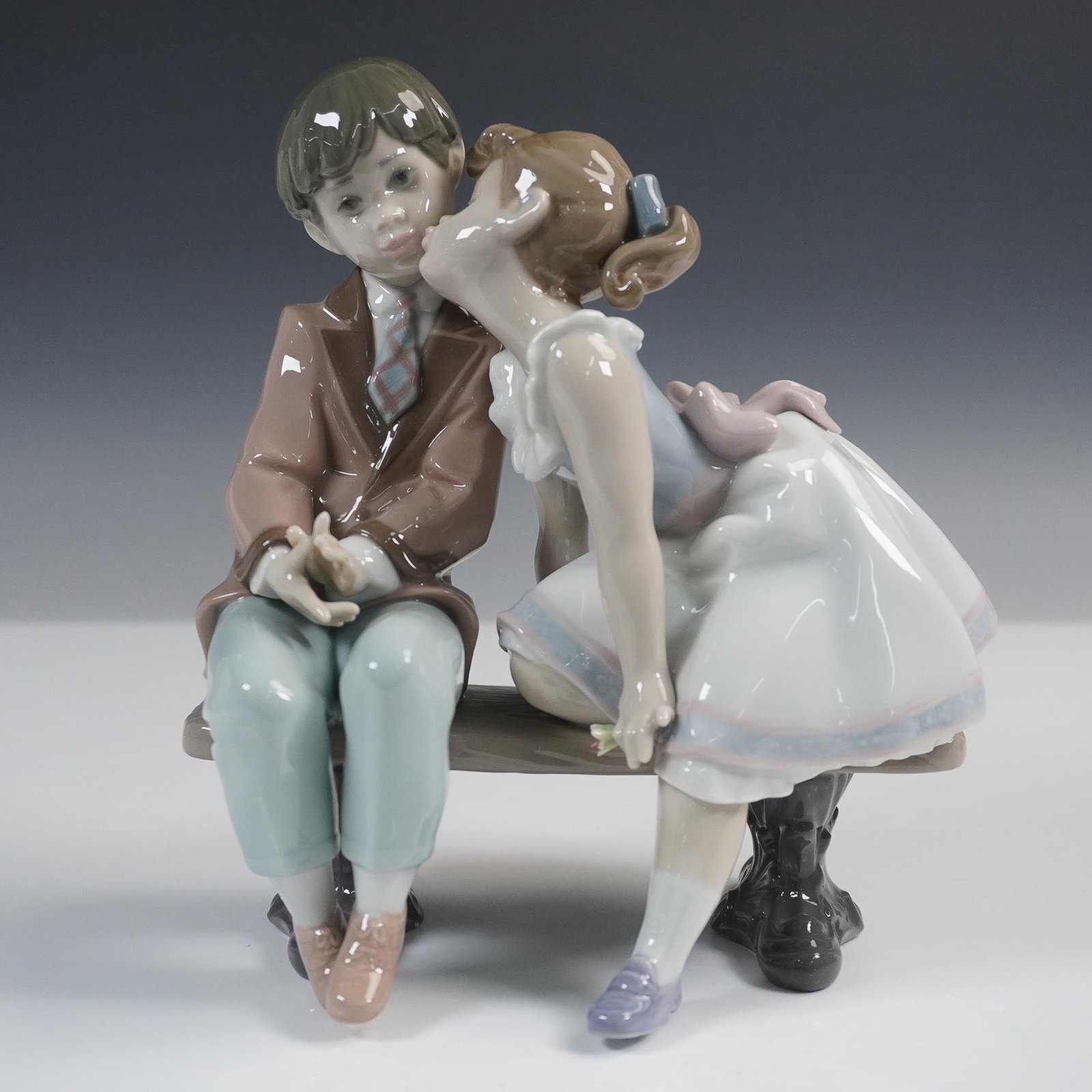Lladro Porcelain Figurine, Ten and Growing 1007635: Lladro porcelain figurine titled Ten and Growing, model number 1007635. Sculpted by Francisco Polope and issued in 1995, this heartwarming piece captures a tender moment between two children seated on