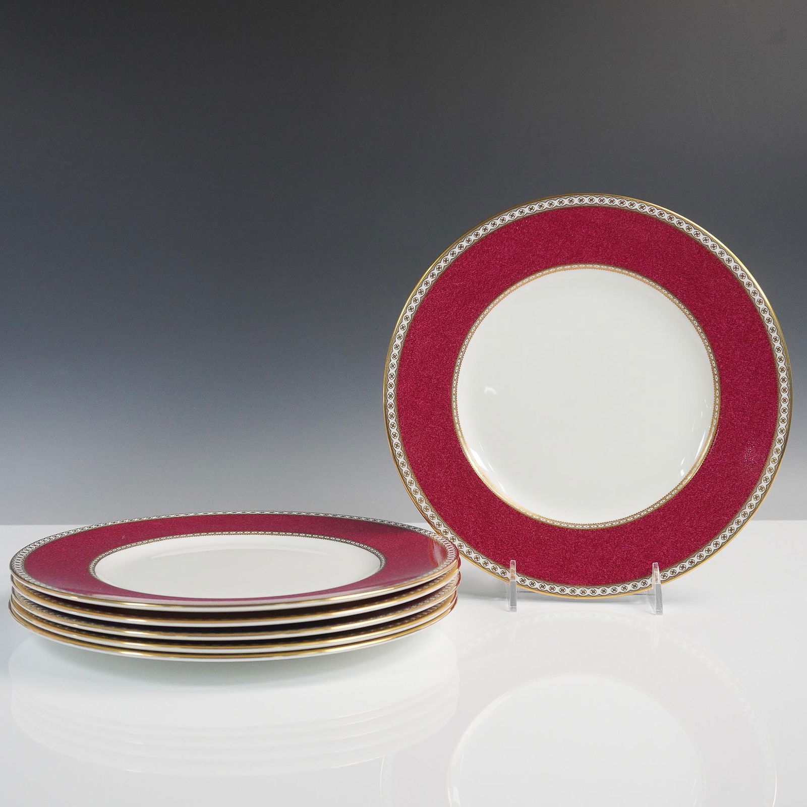 6pc Wedgwood Bone China Ulander Red Dinner Plates: A set of six elegant Wedgwood bone china dinner plates in the Ulander Red pattern (W1813). These English-made plates feature a rich crimson red border with intricate neoclassical gilt detailing and in