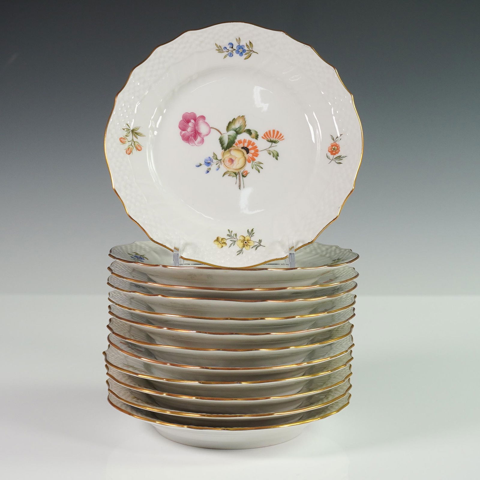 12pc Royal Copenhagen Frijsenborg Cake Plates: Set of twelve Royal Copenhagen porcelain cake plates in the Frijsenborg pattern. Each plate features a hand-painted floral bouquet at the center with scattered floral sprigs near the rim, highlighted