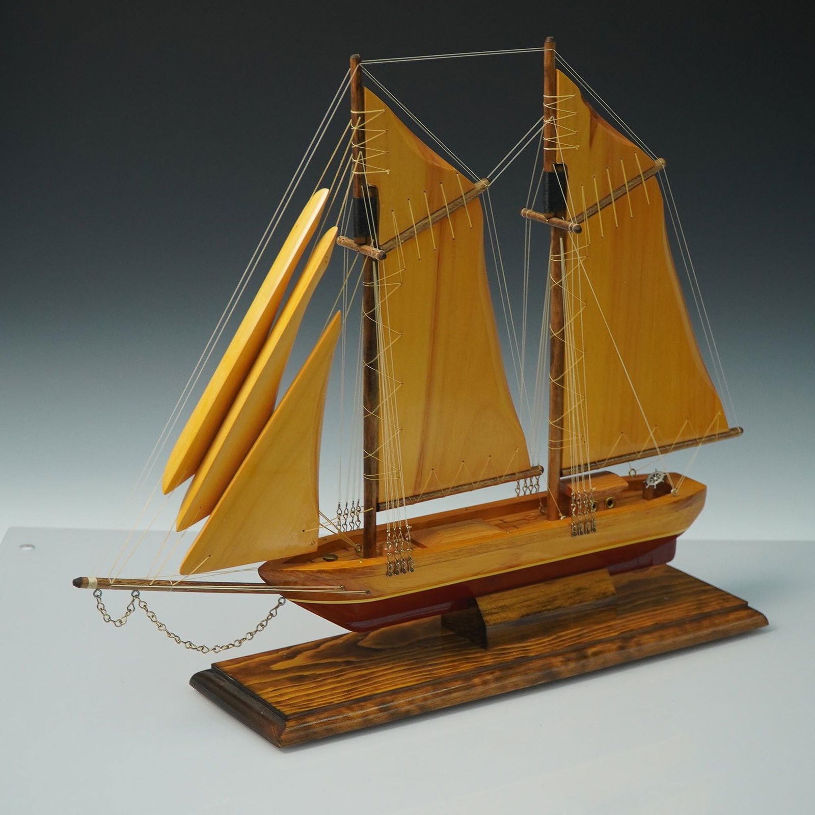 Wooden Model Ship, Shenandoah, 2-Masted Schooner: Handcrafted wooden model ship representing the Shenandoah, a classic two-masted schooner. Constructed with warm-toned wood sails, intricate rigging, and deck details, this model is mounted on a staine