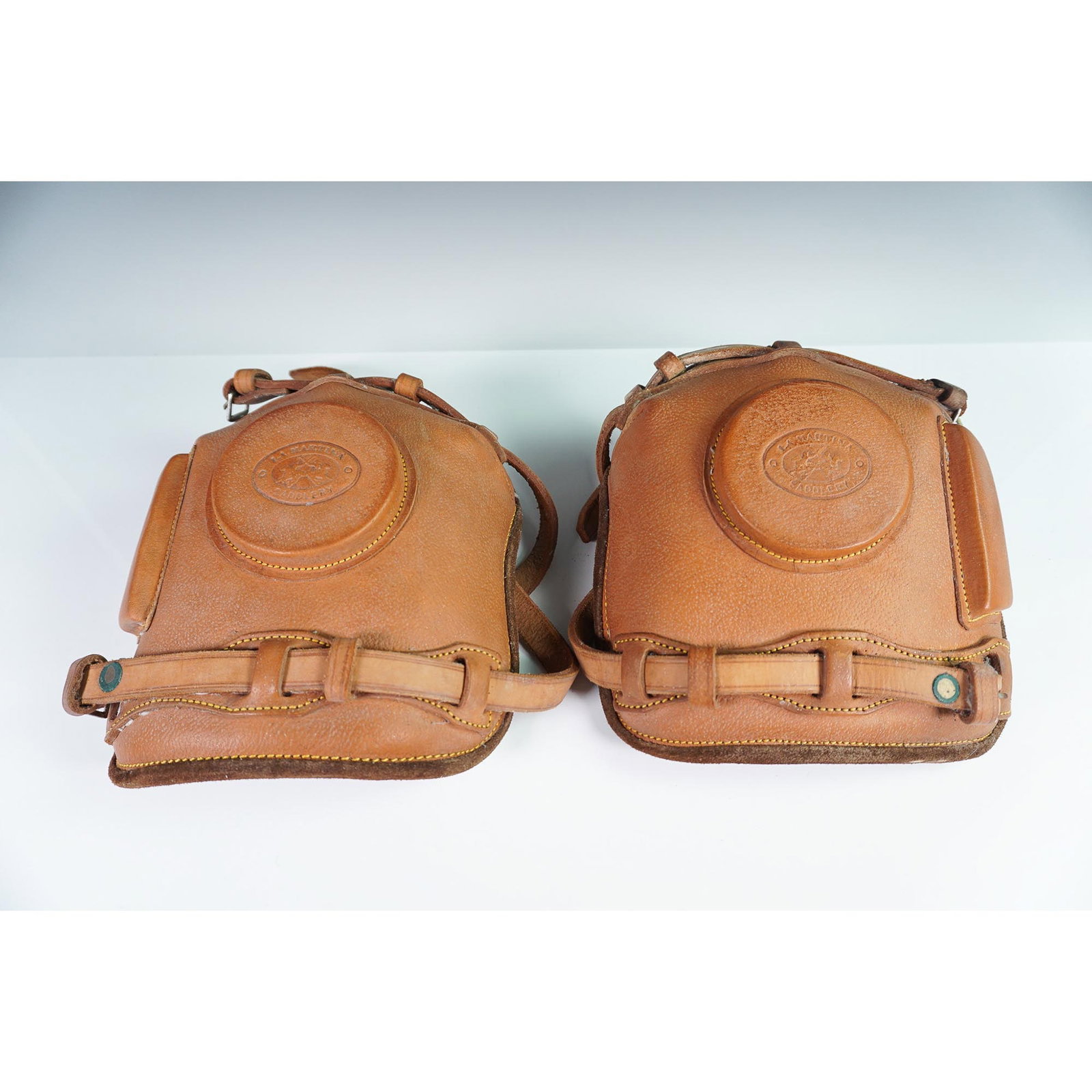 Pair of La Martina Saddlery Leather Polo Knee Guards: Crafted by La Martina Saddlery, this pair of leather polo knee guards is designed for both protection and durability in high-impact equestrian sports. The guards feature a molded leather exterior with