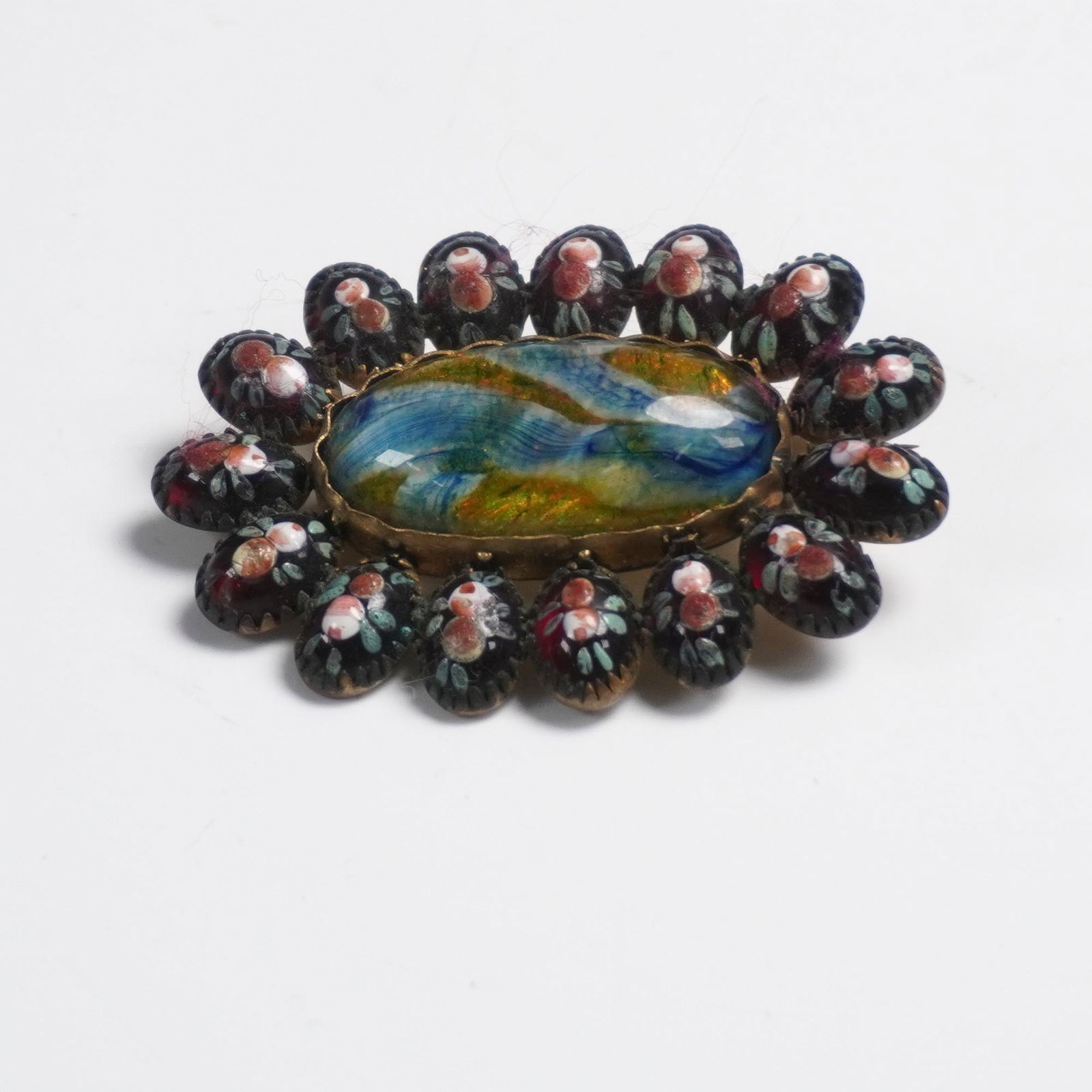 Antique Italian Micro Mosaic and Foil Glass Brooch: Oval brooch featuring a vibrant art glass cabochon with iridescent foil backing at center, surrounded by a meticulously detailed border of Italian micro mosaic glass. The micro mosaic elements depict