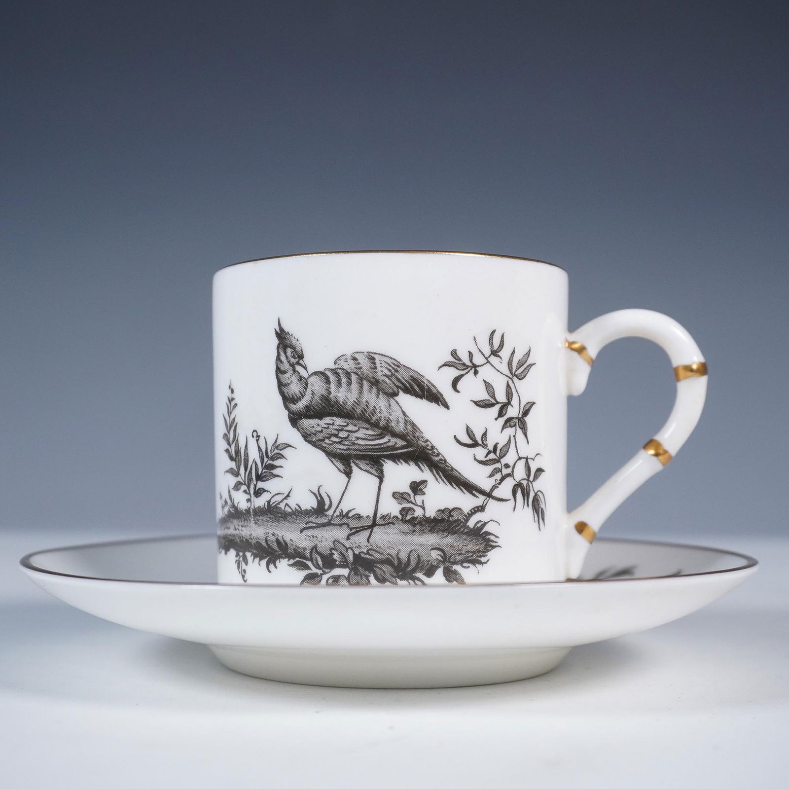 Royal Worcester Demitasse Cup and Saucer Set: Royal Worcester fine bone china demitasse cup and saucer set featuring intricate black botanical and bird illustrations. The petite cylindrical cup depicts a finely detailed game bird in a naturalisti