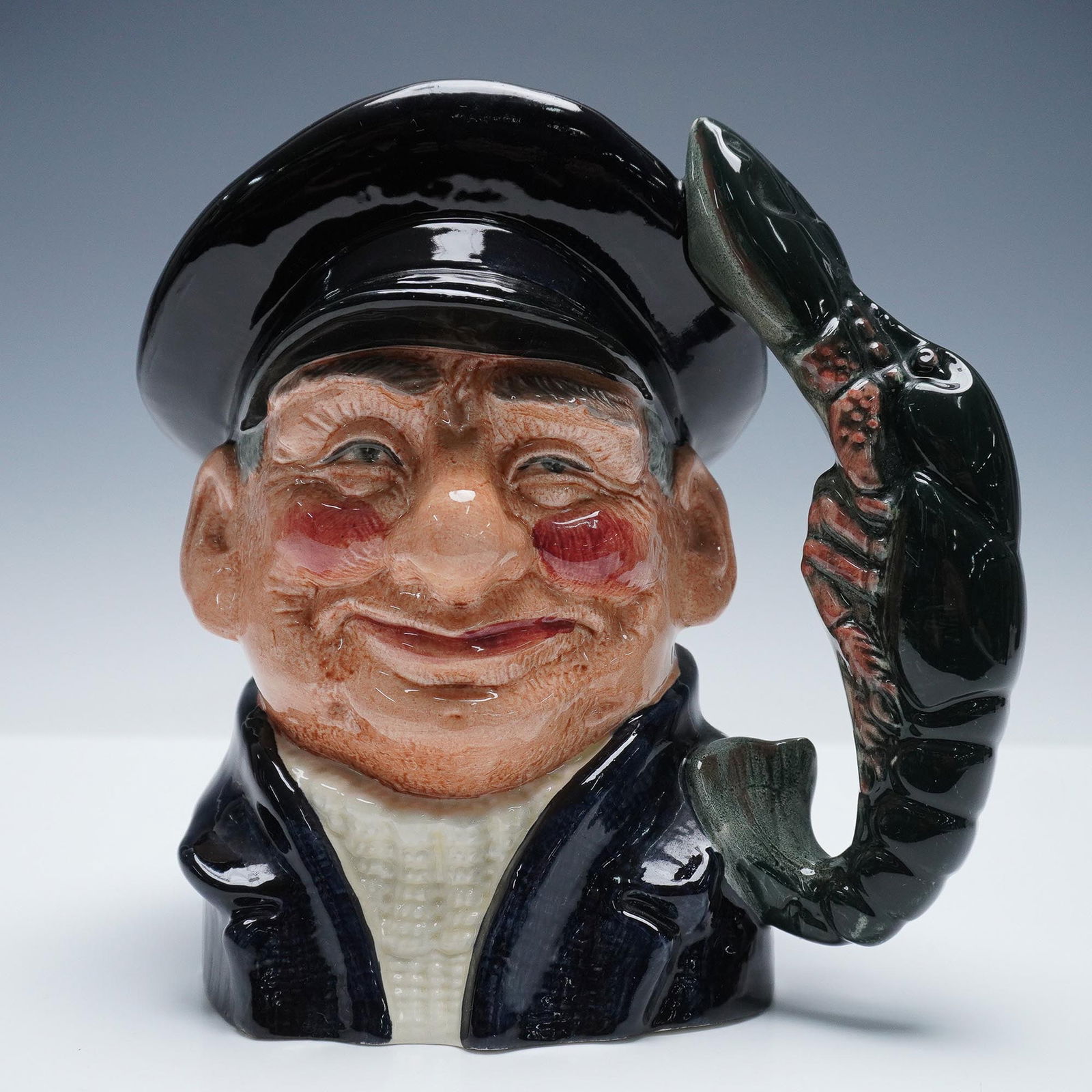 Royal Doulton Large Character Jug, Lobster Man D6617: This figural ceramic jug features a jovial fisherman wearing a dark cap and coat, with a large lobster forming the handle. Artist: David B. Biggs Issued: 1968-1991 Dimensions: 7"W x 8"H Country of Ori