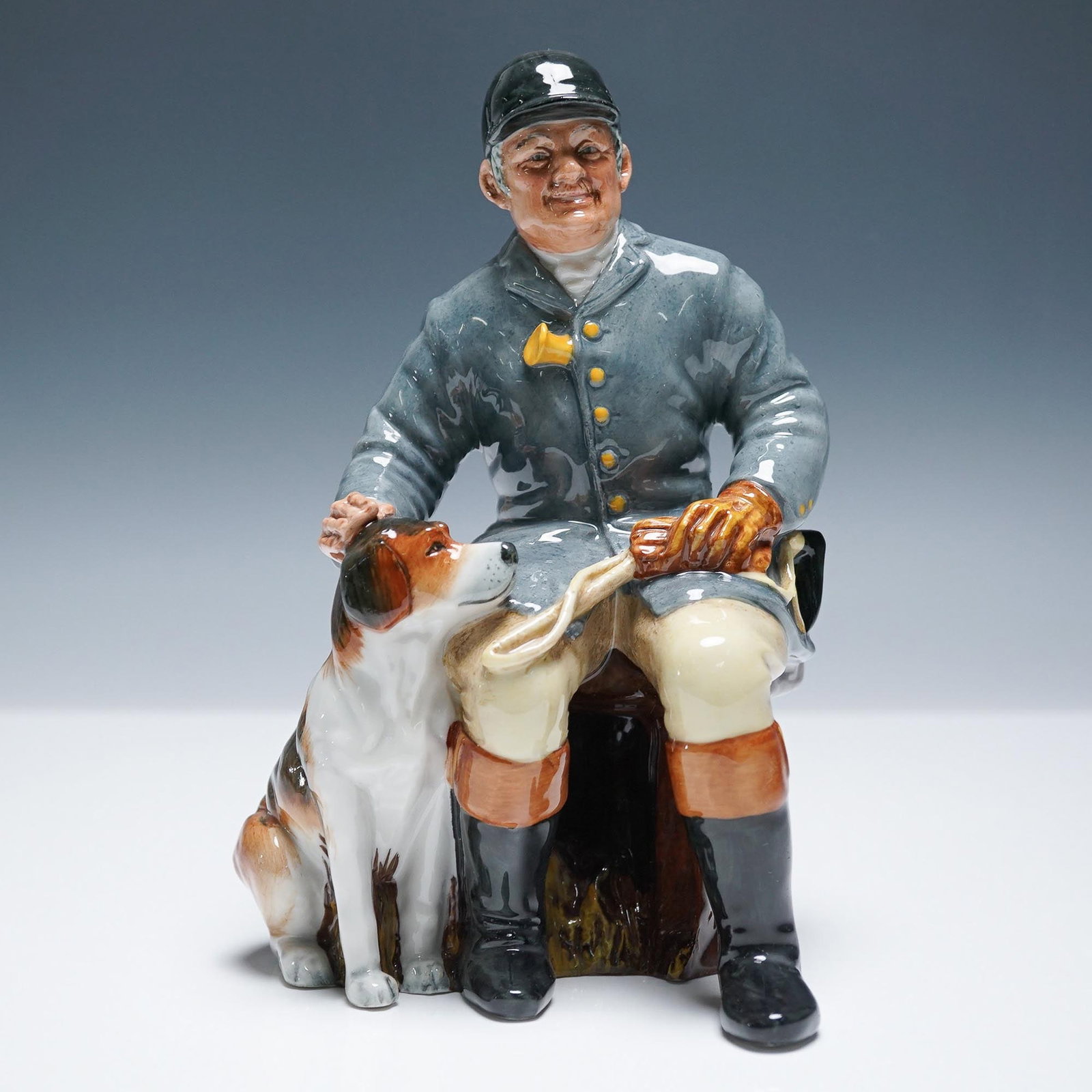 Huntsman HN2492 - Royal Doulton Figurine: Royal Doulton figurine titled The Huntsman HN2492, depicting a seated man in riding attire with a loyal hunting dog at his side. Sculpted by Stanley J. Taylor, this figure captures the warmth and bond