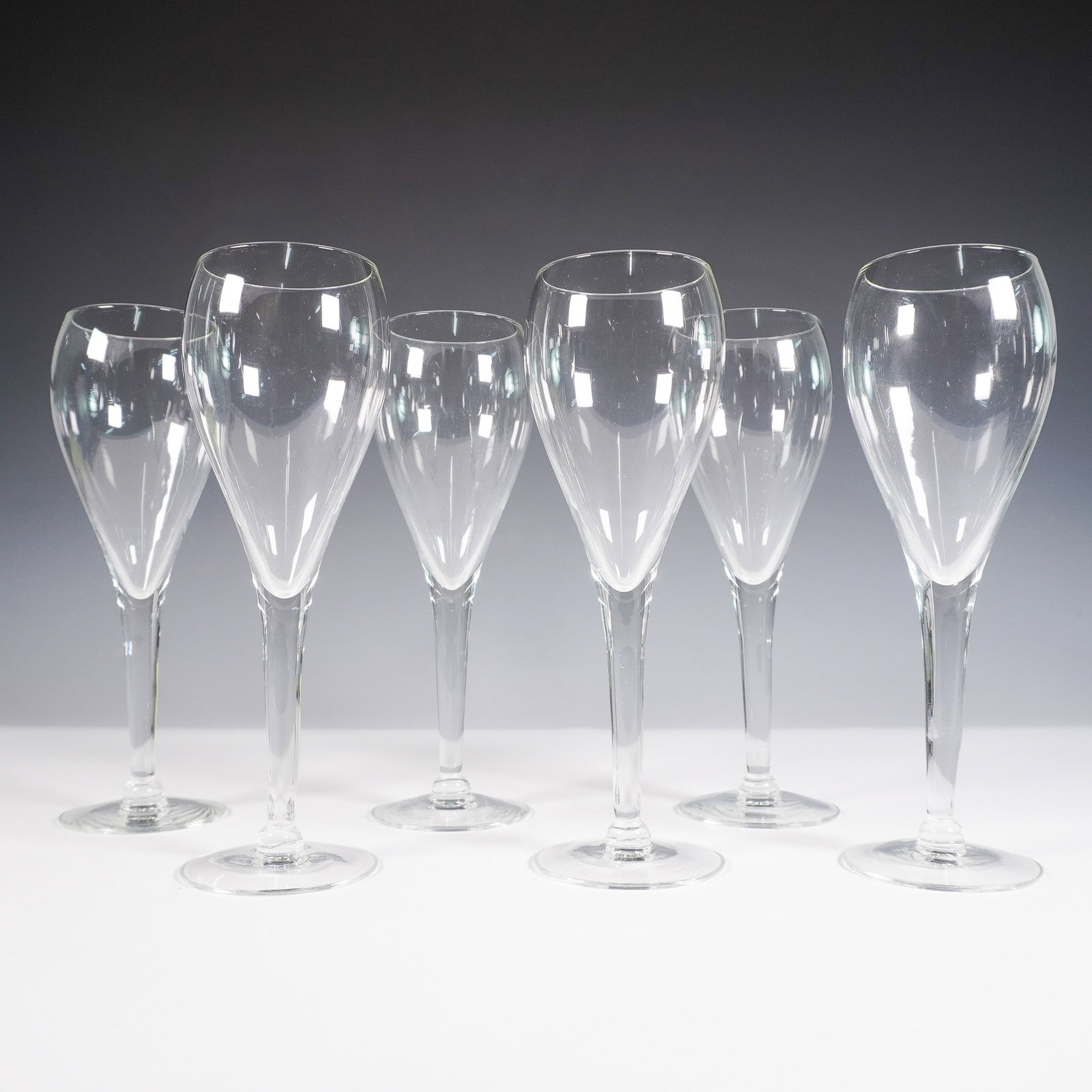 6pc Clear Champagne Flutes: Set of six elegant clear champagne flutes featuring a tapered bowl, slender stem, and round foot. Unmarked but finely crafted, these glasses offer a classic silhouette suitable for both contemporary a