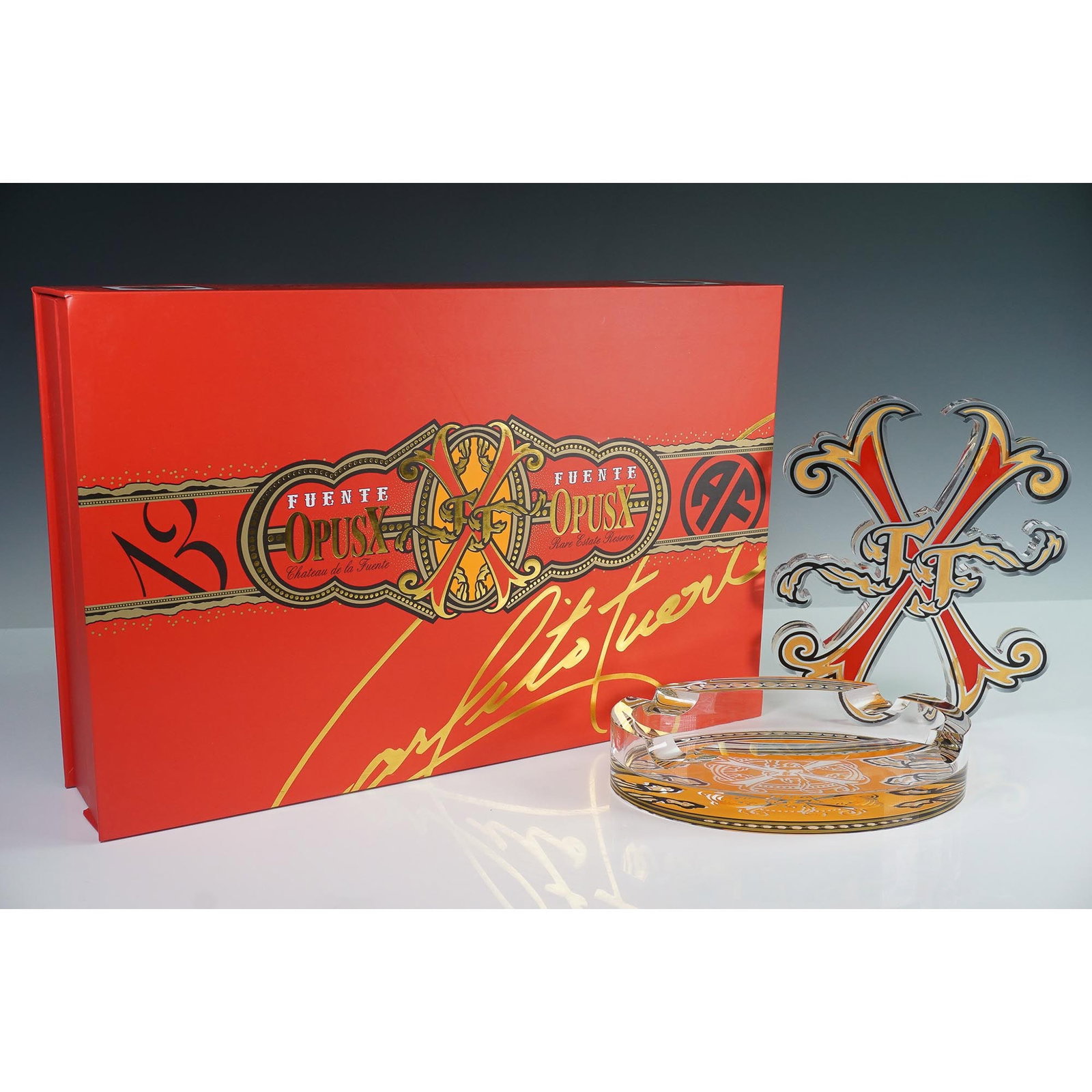 Arturo Fuente OpusX The Fuente Story Collection Cigar Ashtray: A limited edition two piece ashtray presented in an eye catching red and gold travel box bearing the one of a kind OpusX branding and Carlito Fuente's signature. This collectible set includes a thick 