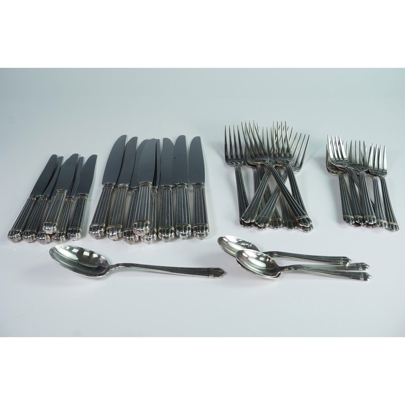 35pc Christofle Tableware Utensil Set, Aria Gold: Extensive flatware collection by Christofle, France, crafted in silverplate with gold-tone accent rings at the base of each handle. The design features fluted handles ending in a rounded, scalloped ti