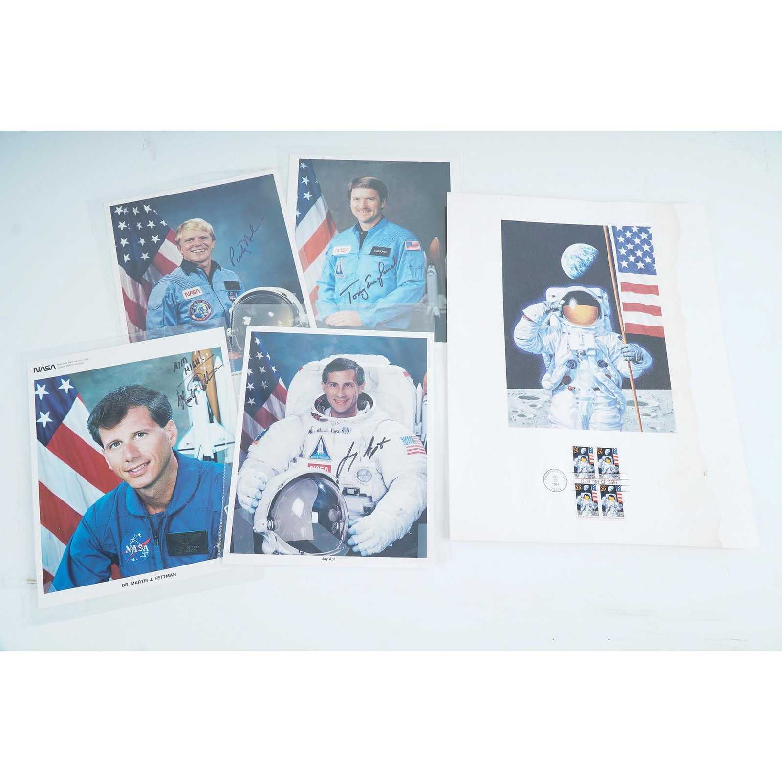 5pc NASA Astronaut Signed Photos and 1994 Moon Landing Stamp Sheet: Collection of five signed 8x10" NASA promotional photographs featuring astronauts George D. Nelson, Anthony W. England, Martin J. Fettman, and Jay Apt. Each image features the astronaut in official NA