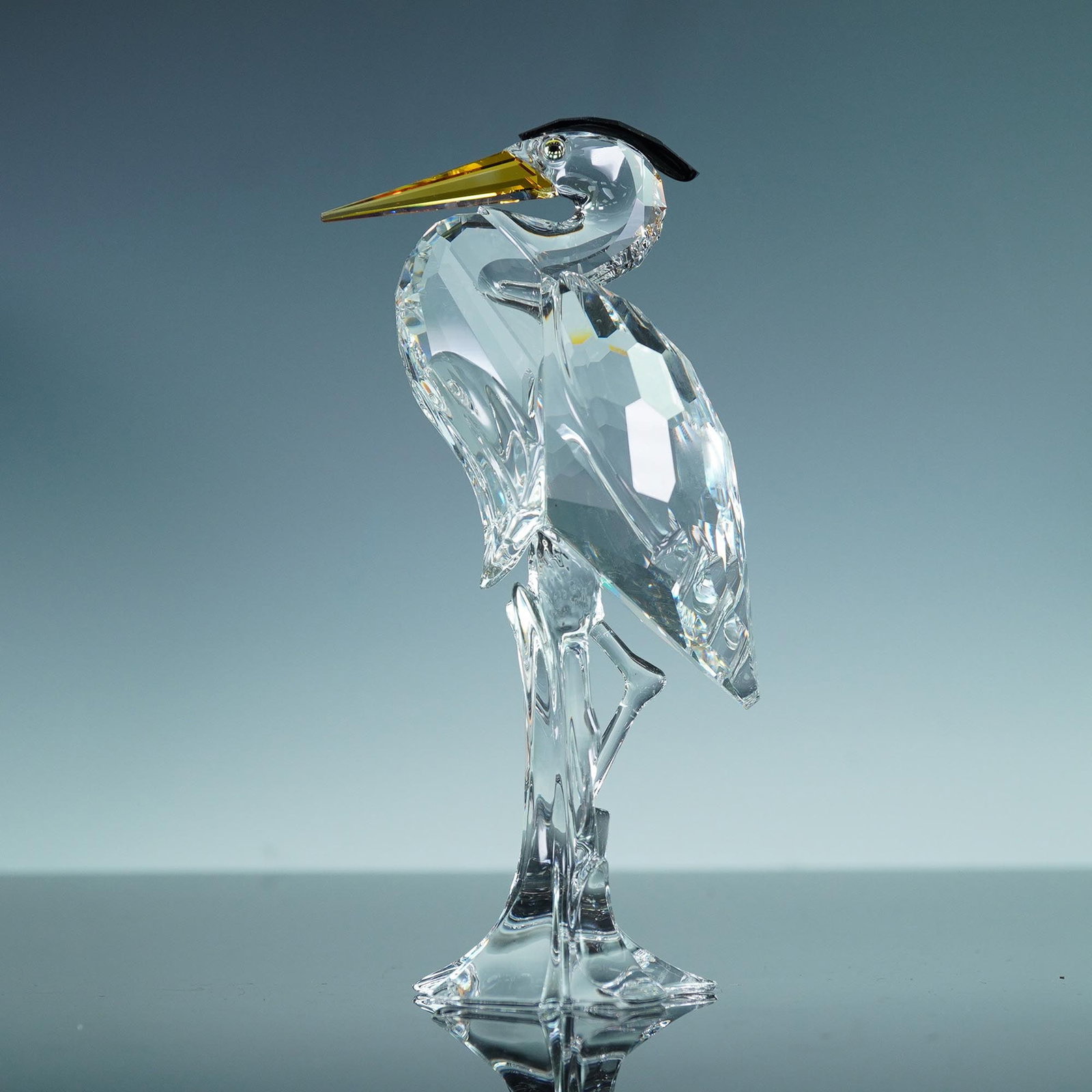 Swarovski Crystal Figurine, Heron, Original Box, 221627: This Swarovski Silver Crystal figurine depicts a majestic heron in a poised stance, expertly crafted in faceted clear crystal. The heron is distinguished by its golden beak, sleek black crest, and str
