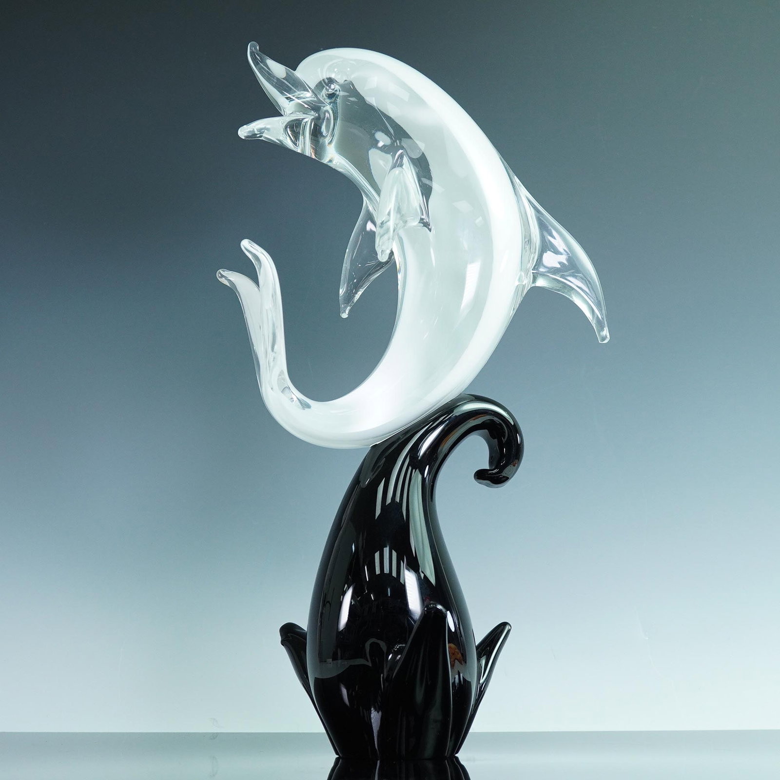 Formia Vetri di Murano Italian Glass Dolphin Sculpture: Featuring a leaping dolphin, the piece is crafted in clear and frosted glass, with the dolphin arched mid-jump and mounted on a black glass wave-form base. The fluid design reflects the Murano glass t