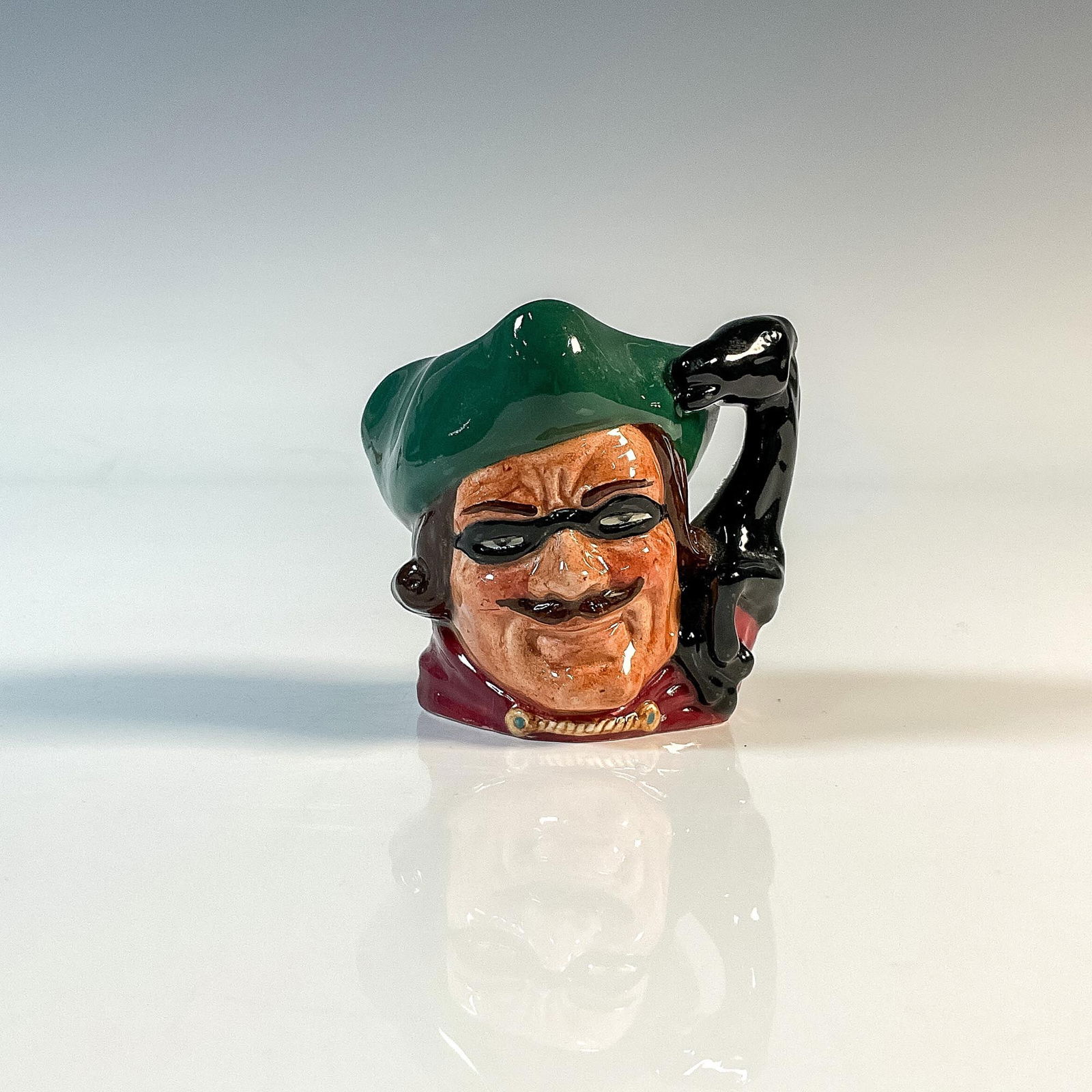 Dick Turpin D6542 (Horse Handle) Mini Doulton Character Jug: Style Two, neck and head of horse handle. Green tricorn; black mask over the eyes, red jacket. Royal Doulton backstamp. Artist: David B. Biggs Issued: 1960 - 1981 Dimensions: 2.25"H Country of Origin: