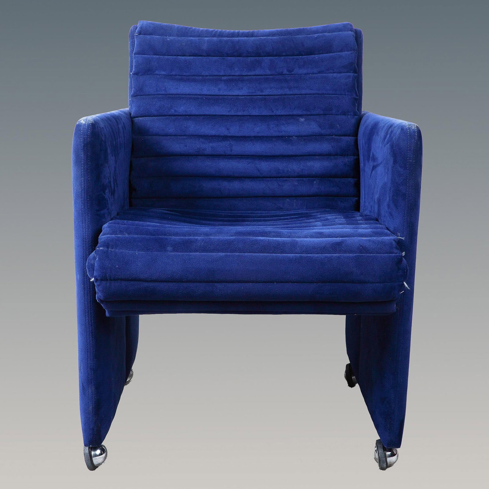 Preview Blue Velvet Lounge Chair on Casters: Elegant Preview blue velvet lounge chair featuring a distinctive ribbed, channel-tufted design for a luxurious and contemporary aesthetic. The plush upholstery is complemented by a sturdy frame and sm