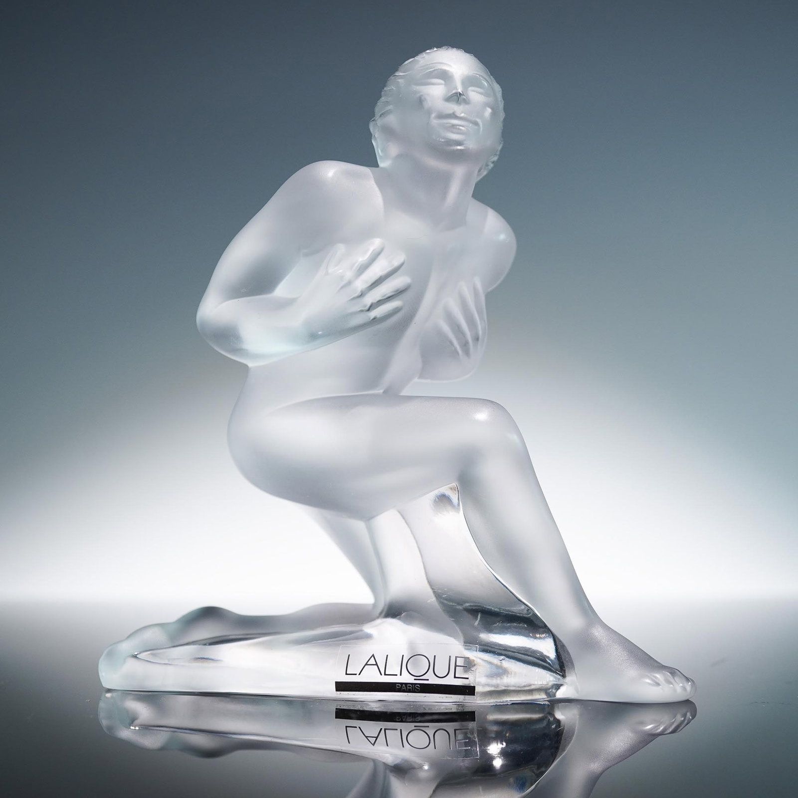 Lalique Crystal Figurine, Serge: A frosted crystal figure depicting a nude male figure in a kneeling pose with hands pressed to his chest and head tilted upward in dramatic expression. Finely crafted in frosted and clear crystal, thi