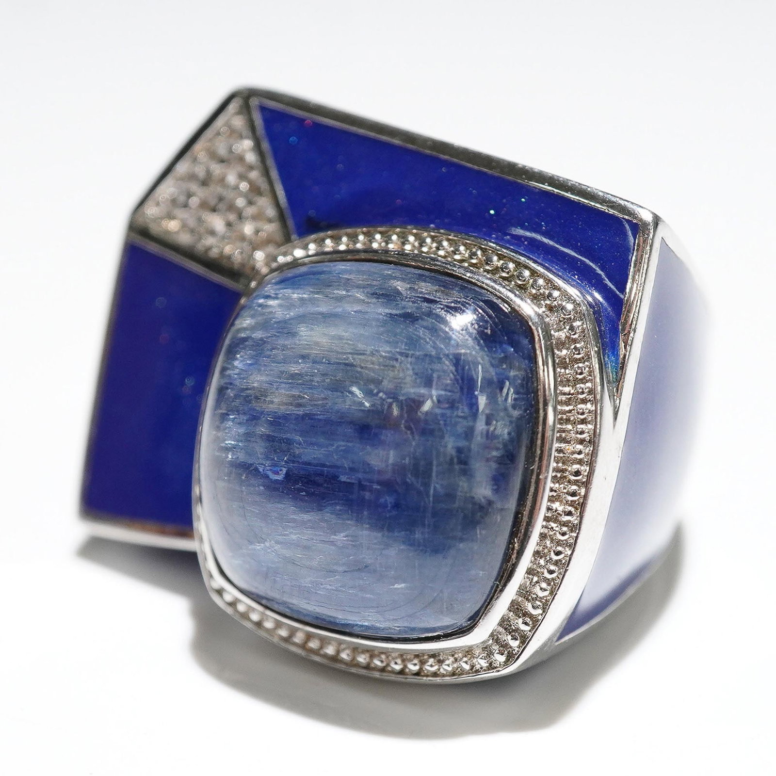 Modernist Blue Enamel and Cabochon Statement Ring: Striking modernist ring featuring deep blue enamel panels in a geometric setting, accented with a large blue cabochon stone at the center and bordered by a textured silver-tone frame. The ring's bold 