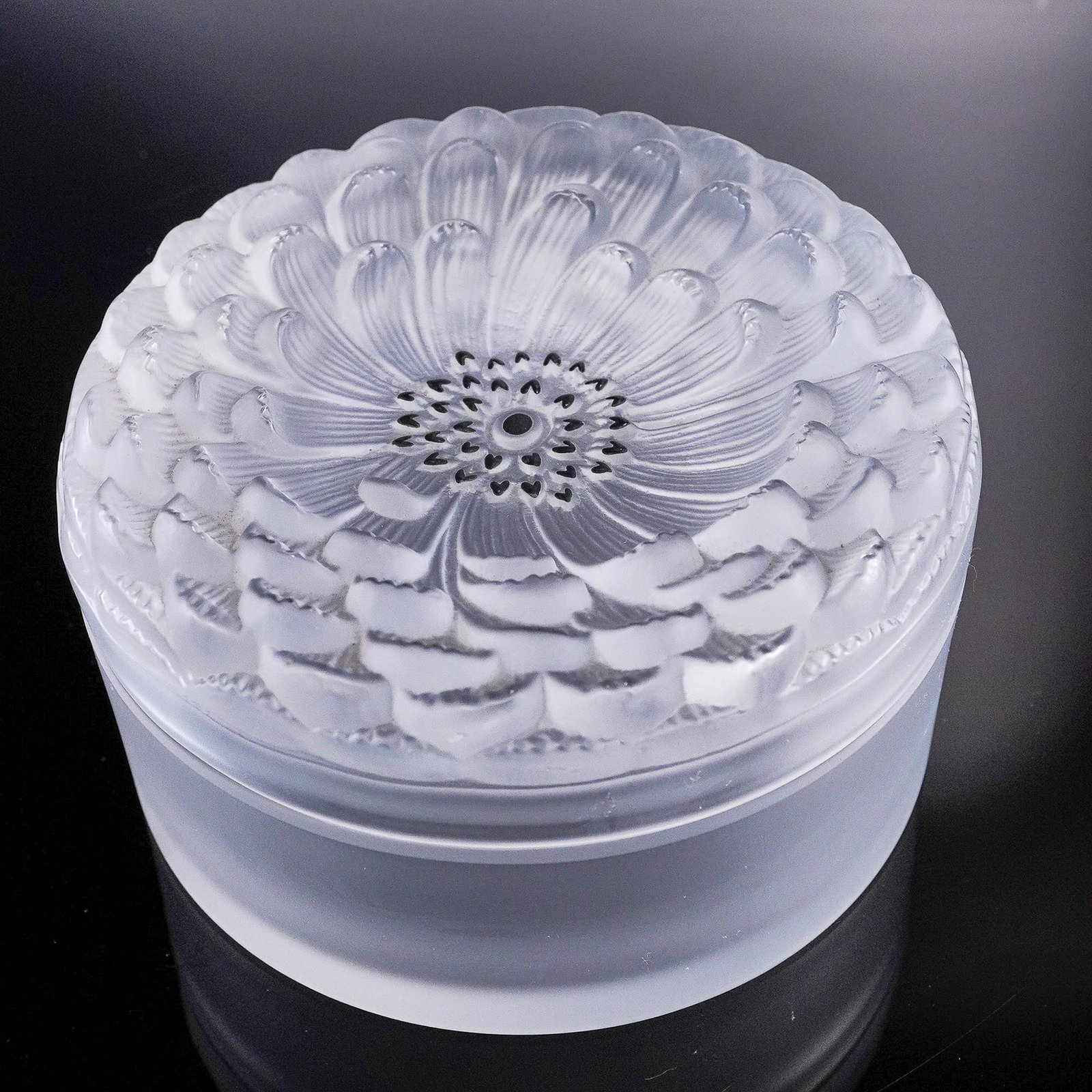 Lalique Crystal Dahlia Dresser Box, Frosted and Clear: This exquisite Lalique crystal dresser box features a lid adorned with a finely sculpted frosted dahlia motif, radiating intricate detail and botanical elegance. The round box is crafted from satin-fi