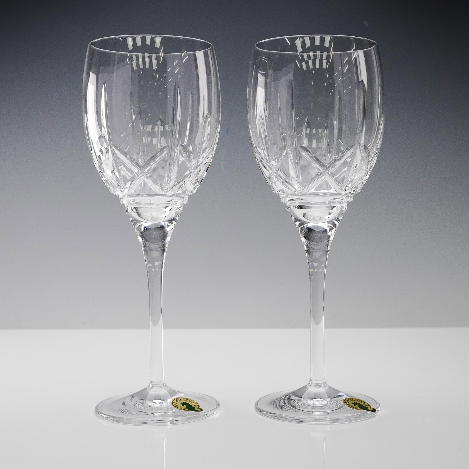 2pc Waterford Crystal Wine Glasses, Marquis: Pair of Waterford crystal wine glasses featuring the classic faceted bowl design with elongated stems. Each glass is etched with the Waterford backstamp and retains the original green and gold seahors
