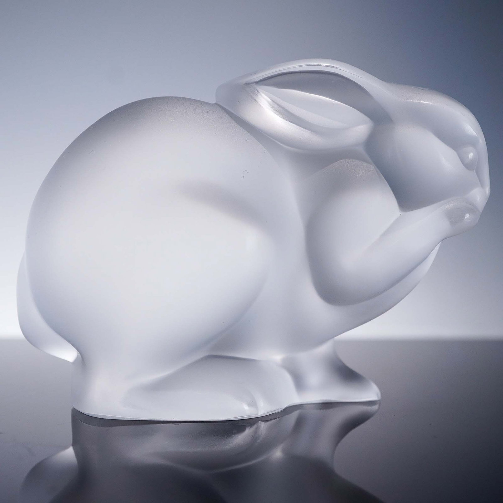 Lalique Crystal Figurine, Frosted Rabbit: This charming Lalique crystal figurine features a softly sculpted rabbit, rendered in frosted glass that enhances its gentle, rounded contours. The smooth surface and delicate detail in the ears and p