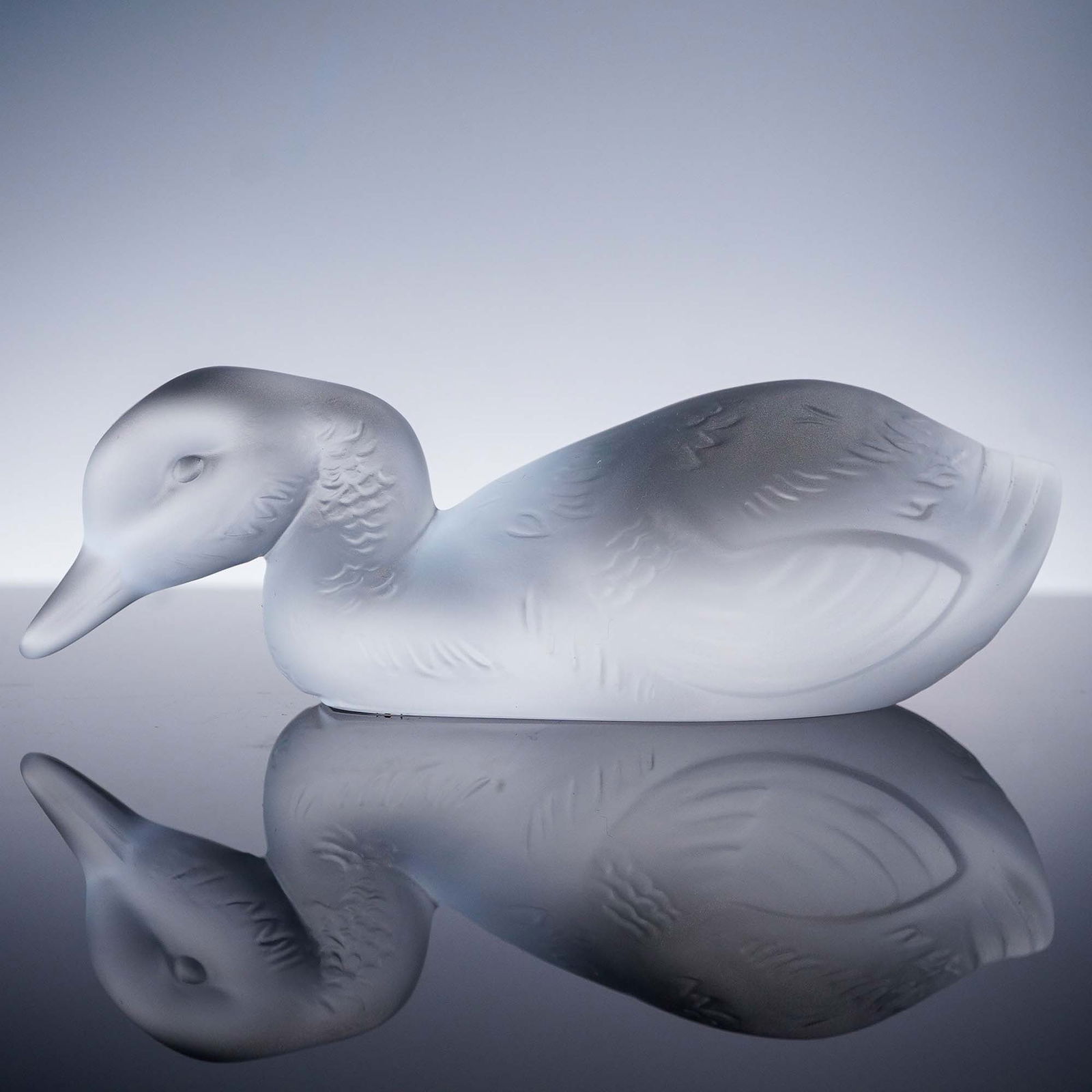Baccarat Clear Crystal Figurine, Duckling: An elegant Baccarat clear crystal figurine depicting a resting duckling, expertly crafted with frosted and smooth finishes to capture the delicate texture of feathers and the gentle curve of the young