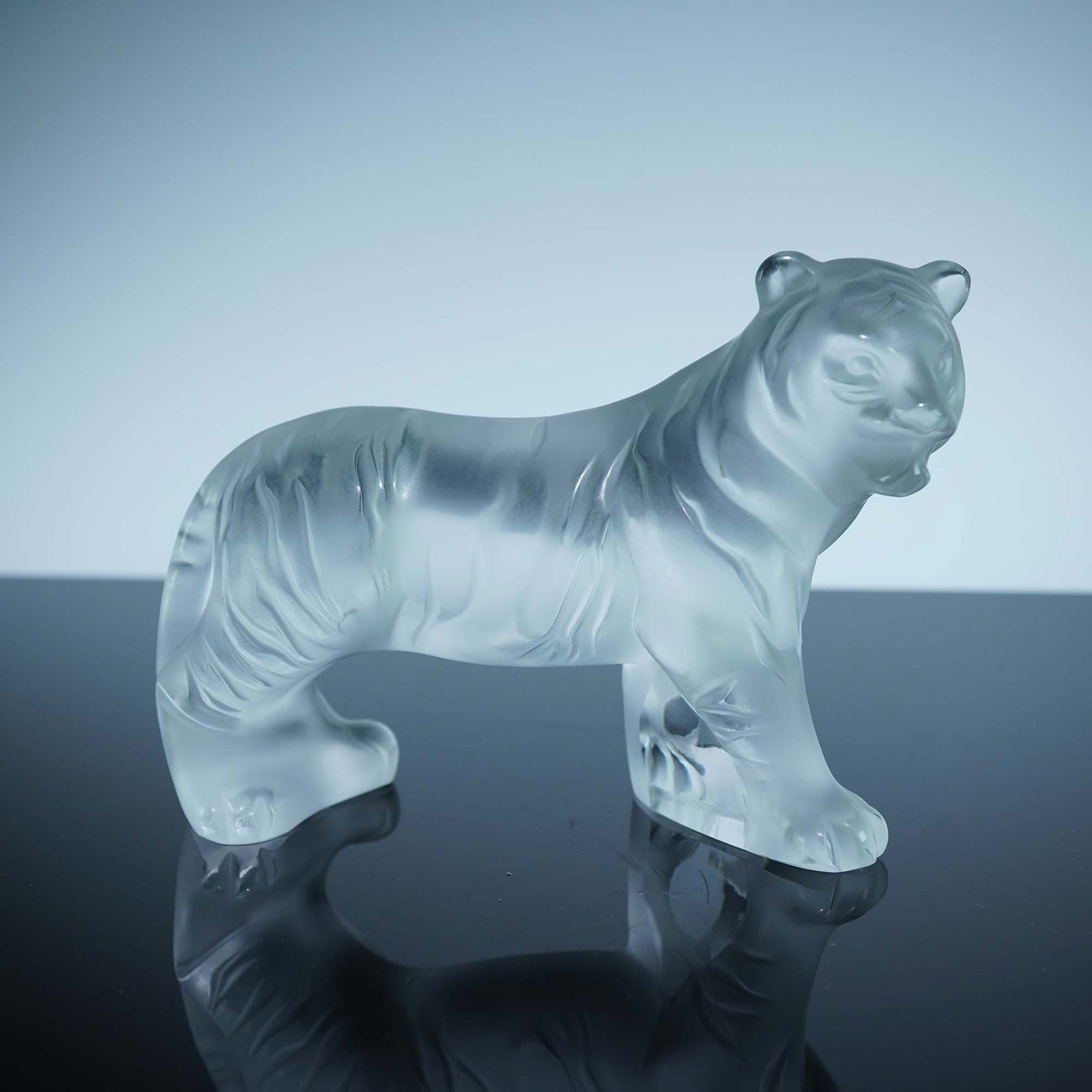 Lalique Crystal Figurine, Frosted Bengal Tiger: Striking Lalique crystal figurine of a Bengal tiger, expertly sculpted in frosted crystal to emphasize its powerful stance and muscular form. The detailed striations along the body evoke the tiger's n