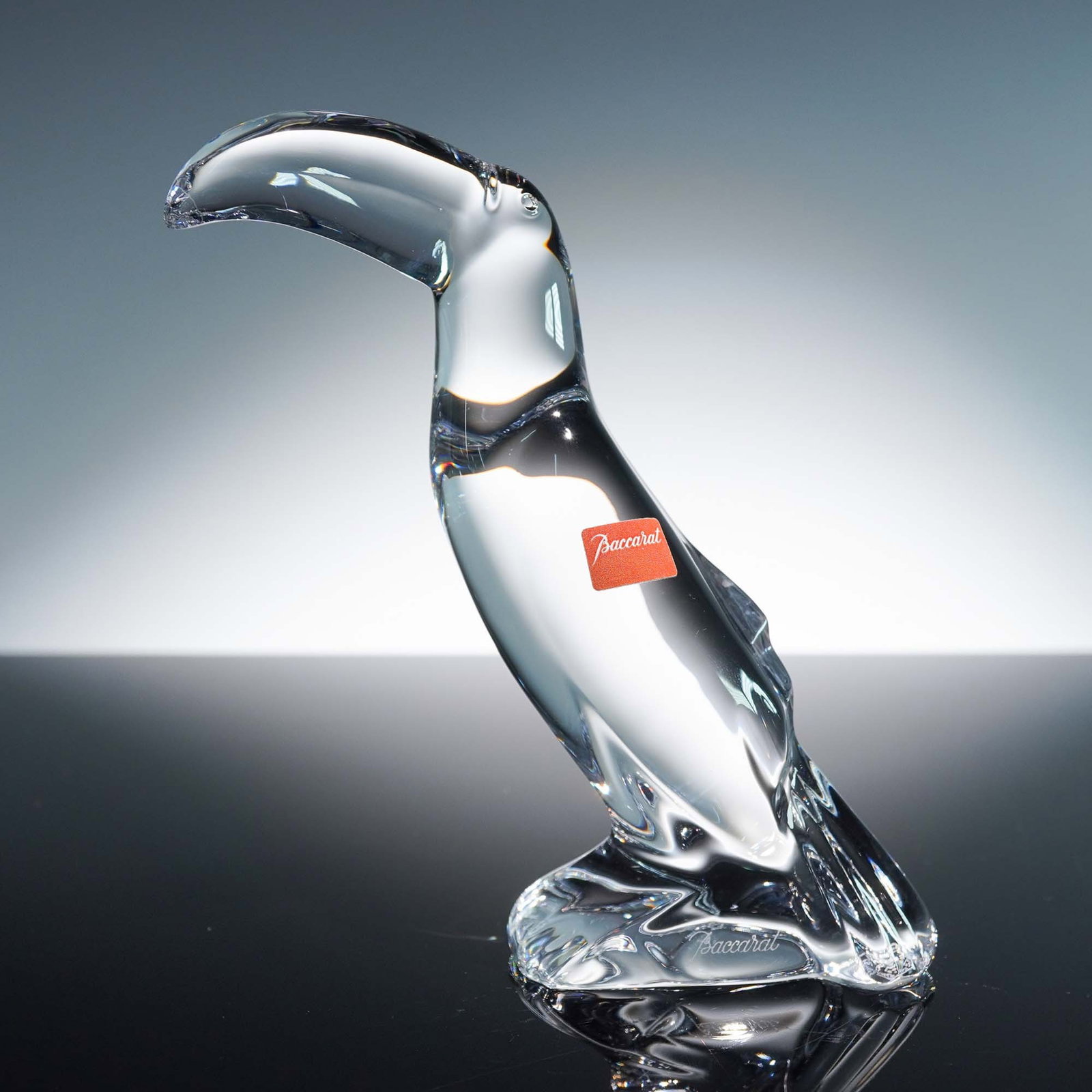 Baccarat Crystal Figurine, Toucan: Masterfully sculpted toucan figurine with modernist profile and rich curvature. Designed beautifully in a clear crystal finish with its enlarged beak. Baccarat backstamp. Dimensions: 5"L x 2"W x 6"H C