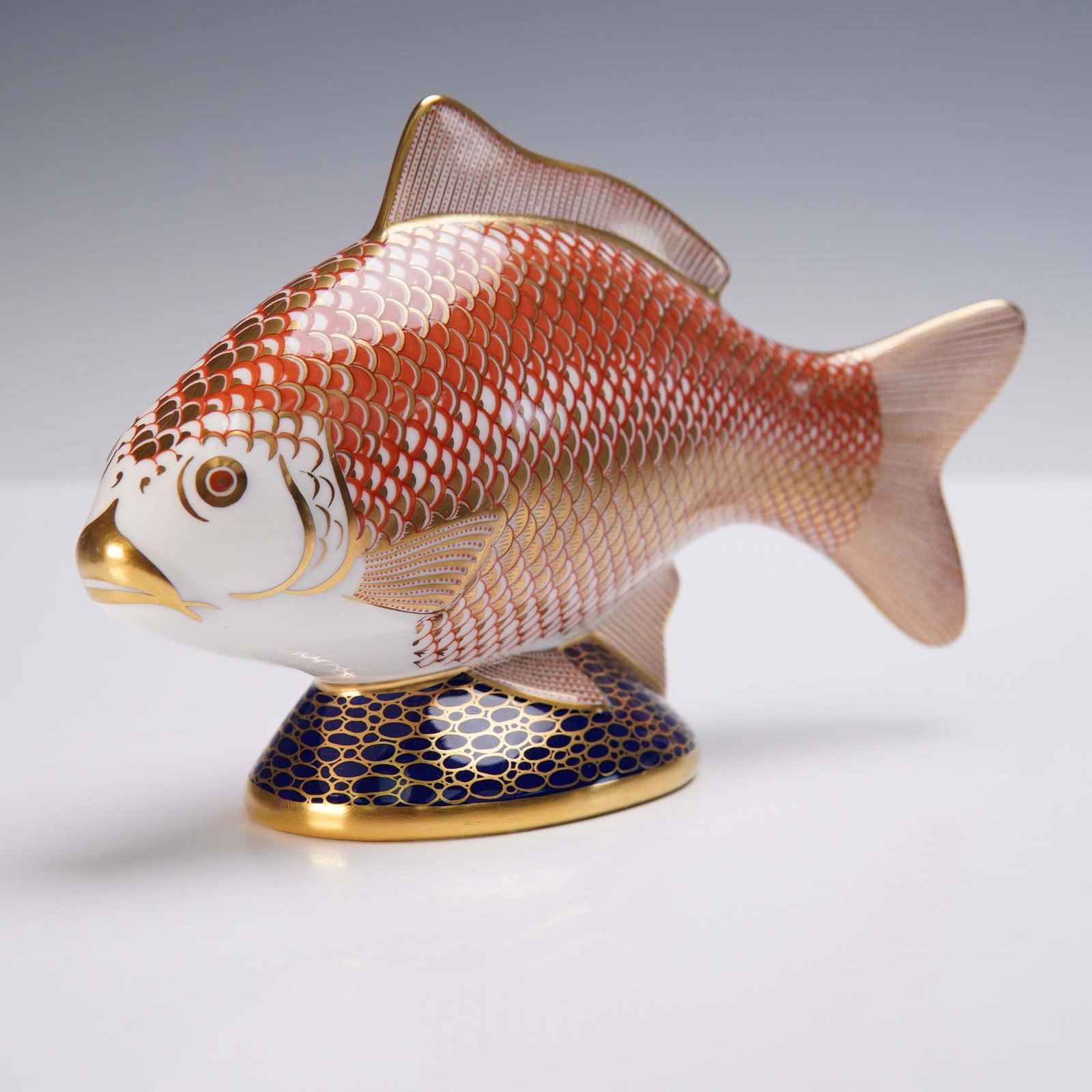 Royal Crown Derby Porcelain Golden Carp Paperweight: This exquisite Royal Crown Derby porcelain figurine represents the Golden Carp, crafted in fine bone china with vivid Imari-inspired colors and lavish 22-karat gold accents. The figurine features intr