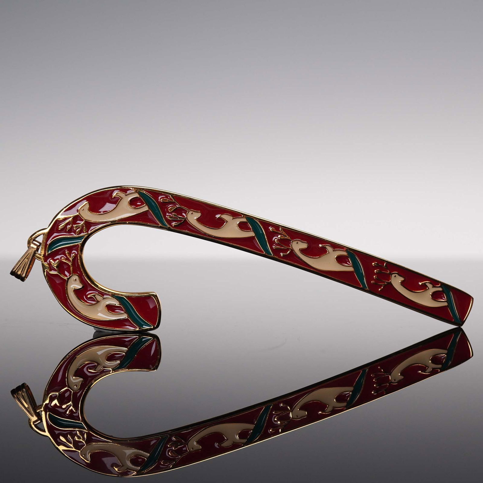 Wallace Silversmiths 1990 Christmas Reindeer Candy Cane Ornament: Wallace Silversmiths holiday ornament from 1990 in the shape of a candy cane, adorned with red, green, and gold-tone enamel over a reindeer motif. The festive design features scrolling reindeer forms