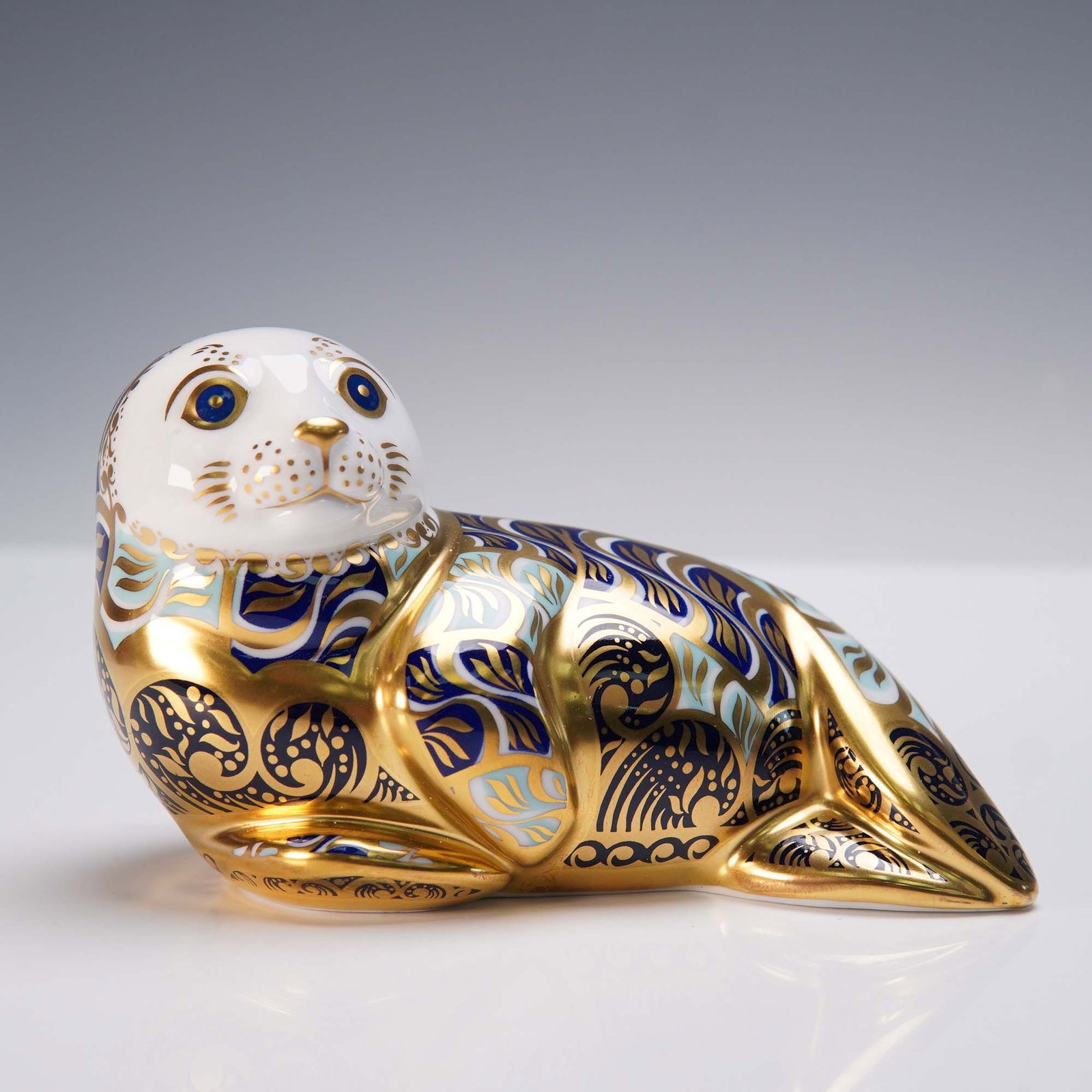 Royal Crown Derby Porcelain Harbour Seal Paperweight: This limited edition Royal Crown Derby porcelain paperweight depicts a Harbour Seal, crafted in fine bone china and adorned with intricate decoration in cobalt blue, aqua, and rich 22 karat gold. The 