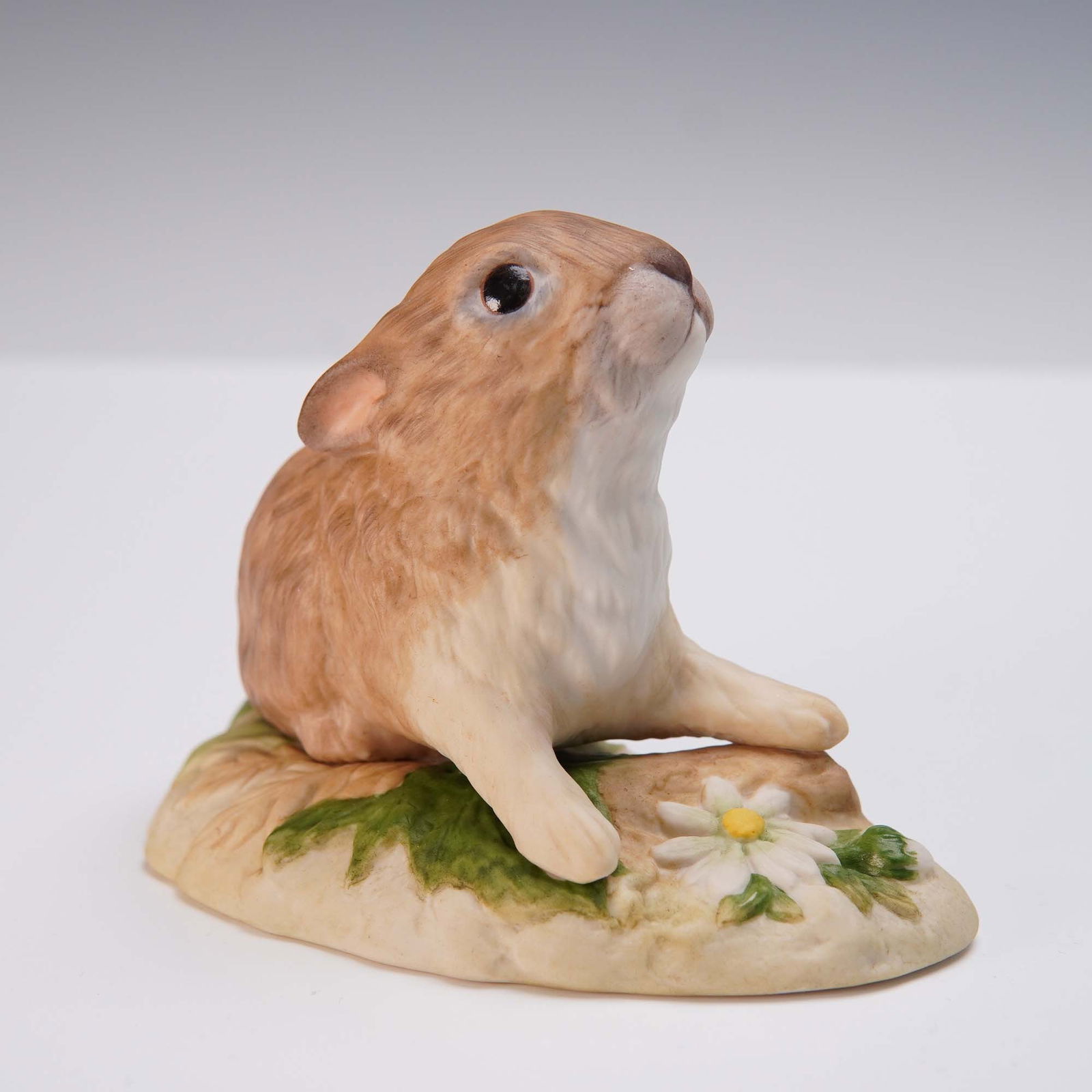 Cybis Porcelain Figurine, Muffet Baby Rabbit: Charming hand-painted porcelain figurine by Cybis, depicting a wide-eyed baby rabbit seated on a naturalistic base with a white flower. The delicate matte glaze enhances the realistic fur texture and